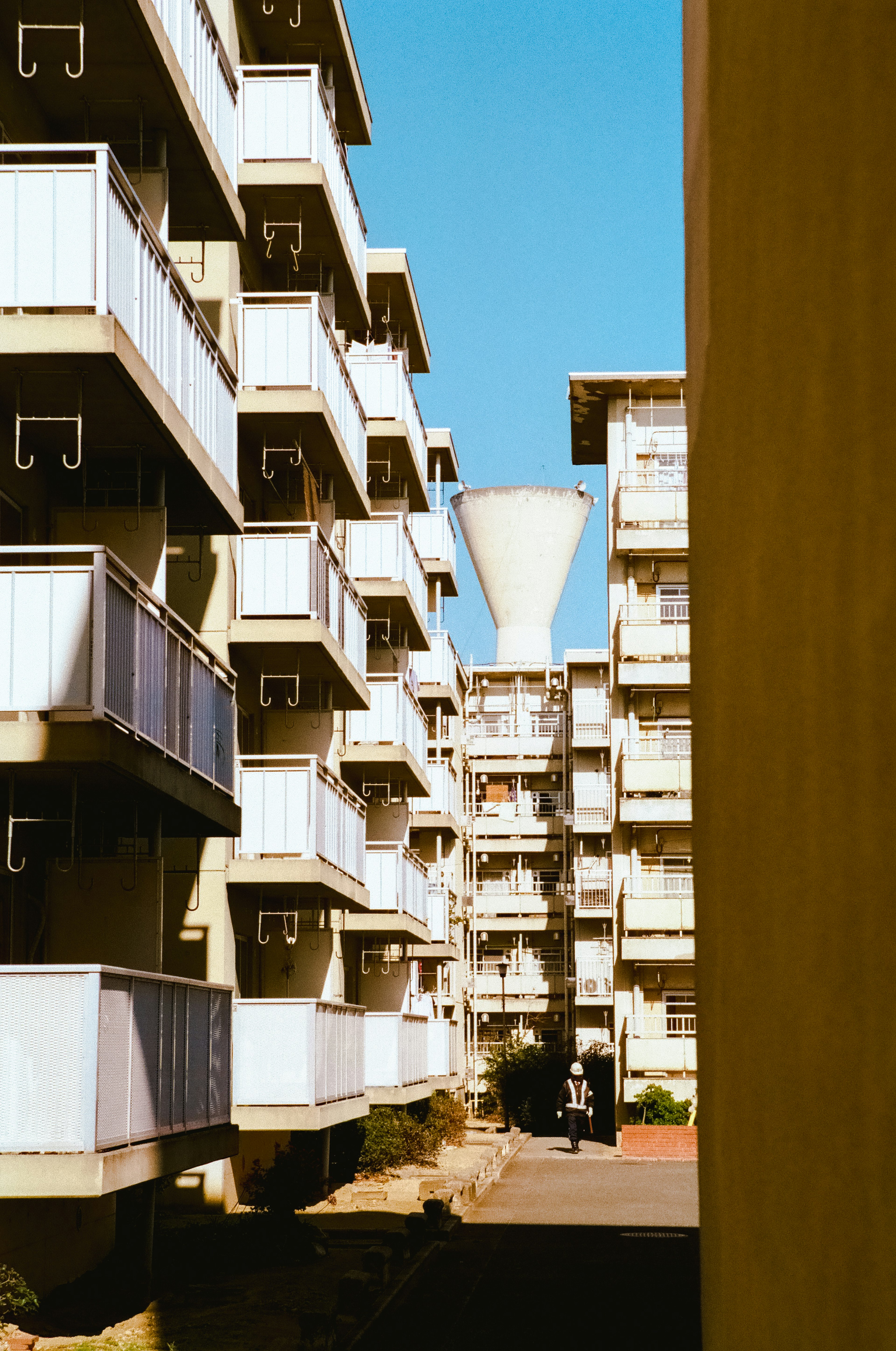 Water tower visible between high-rise apartment buildings under a clear blue sky