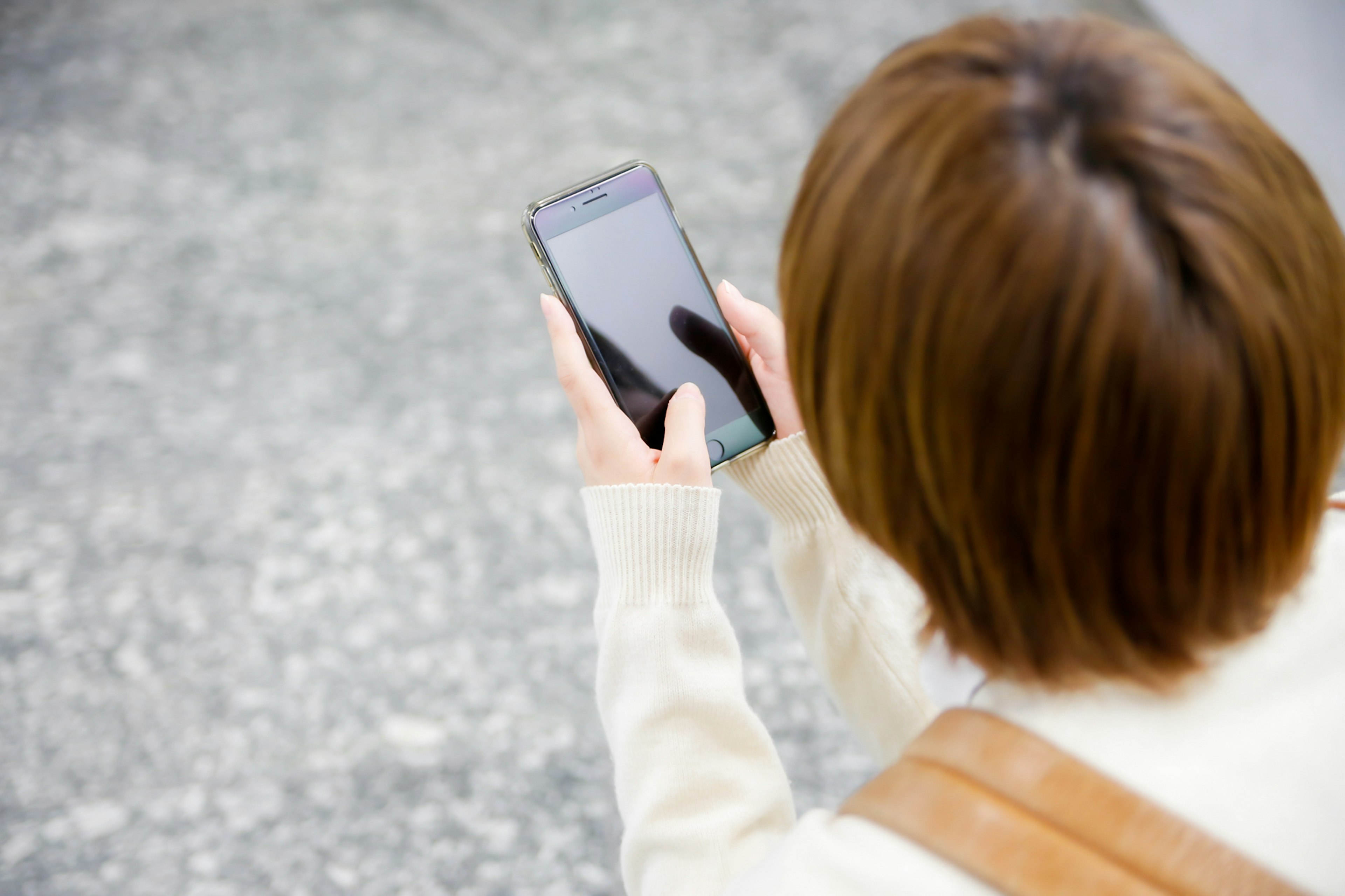 Giovane donna che tiene uno smartphone vista da dietro