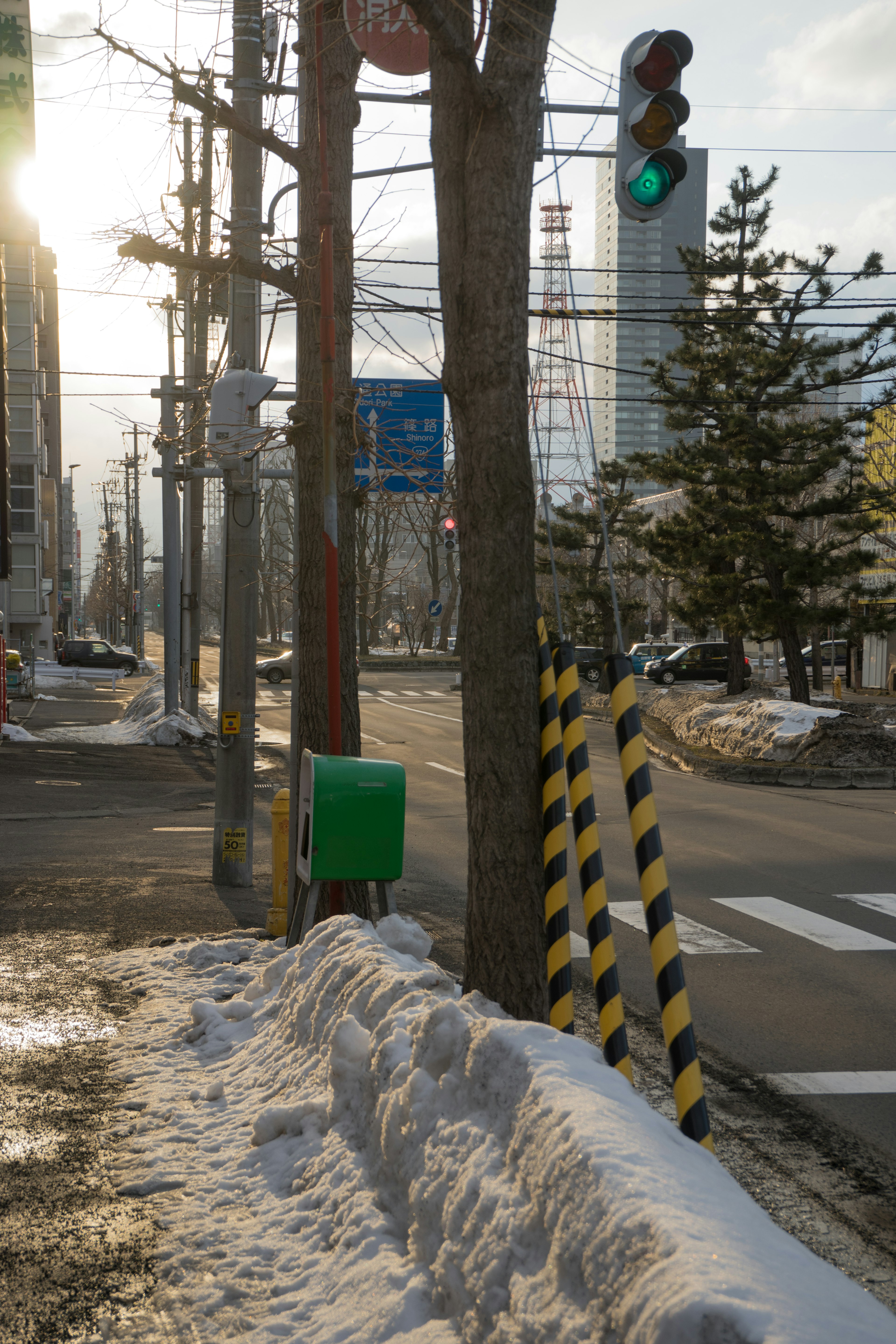 雪の積もった道路と緑のボックスがある街角の風景