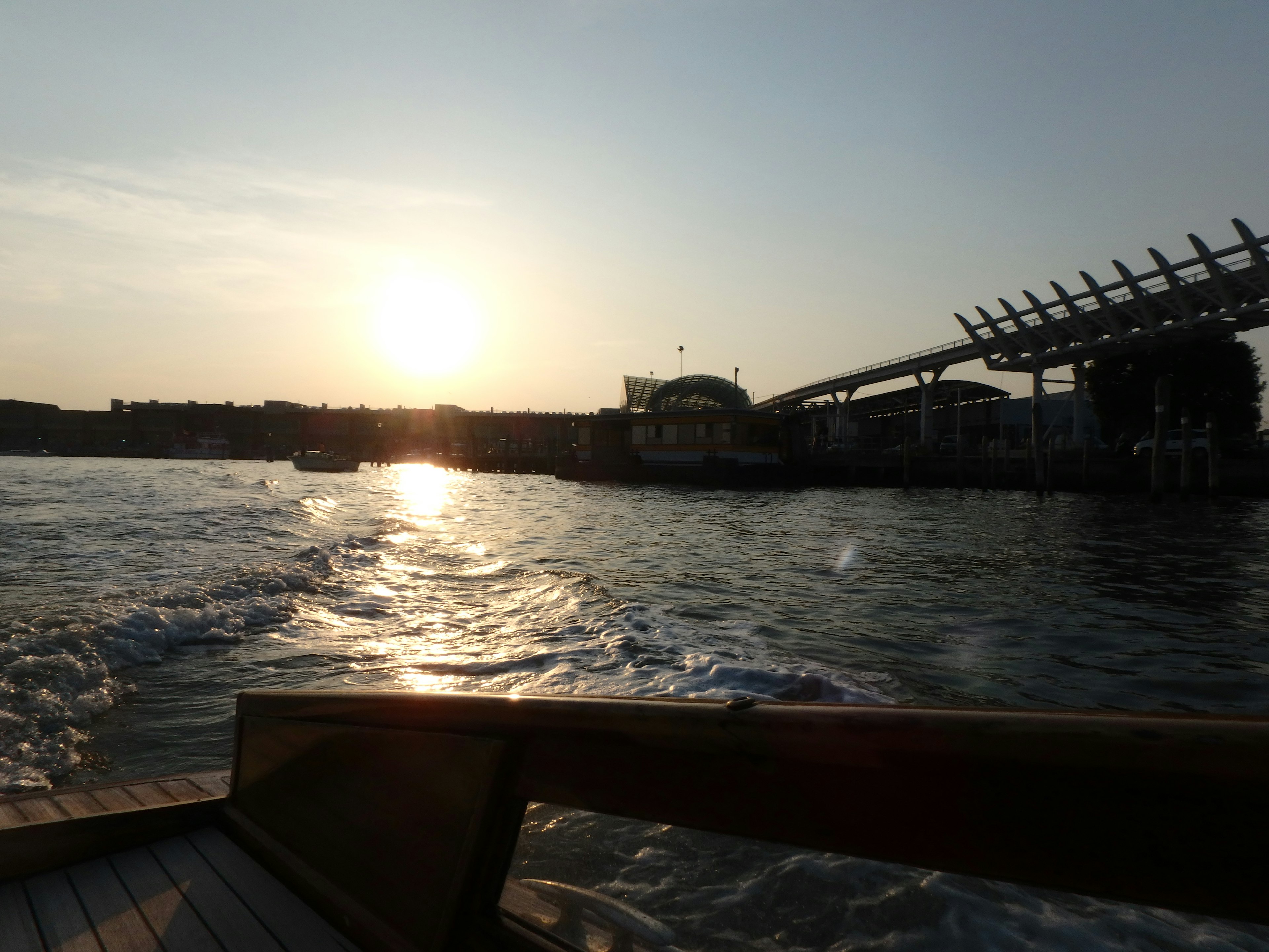 夕日が水面に反射する美しい風景 船の側面と岸の建物が見える