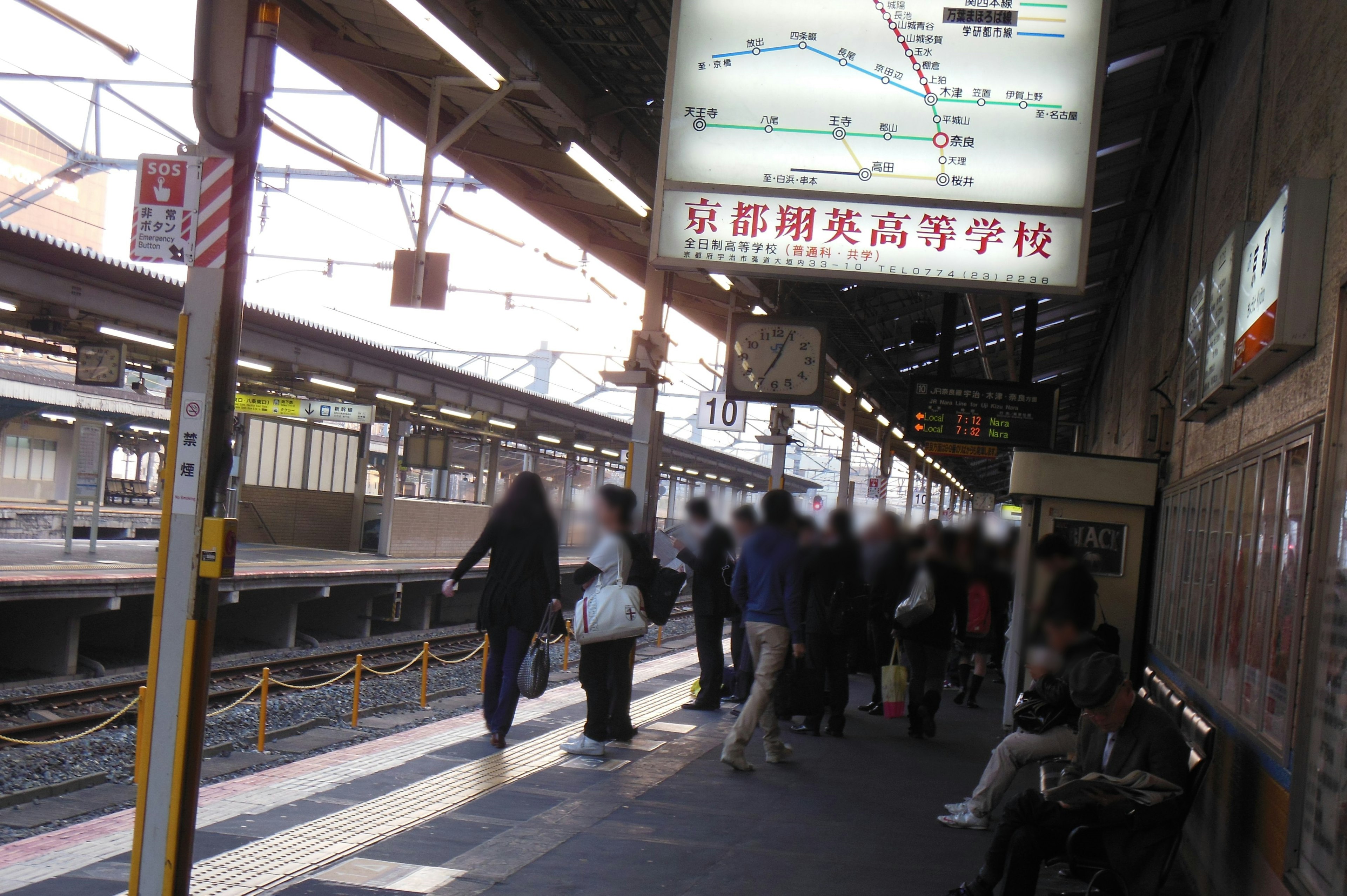 Crowd at a train station platform with an electronic display