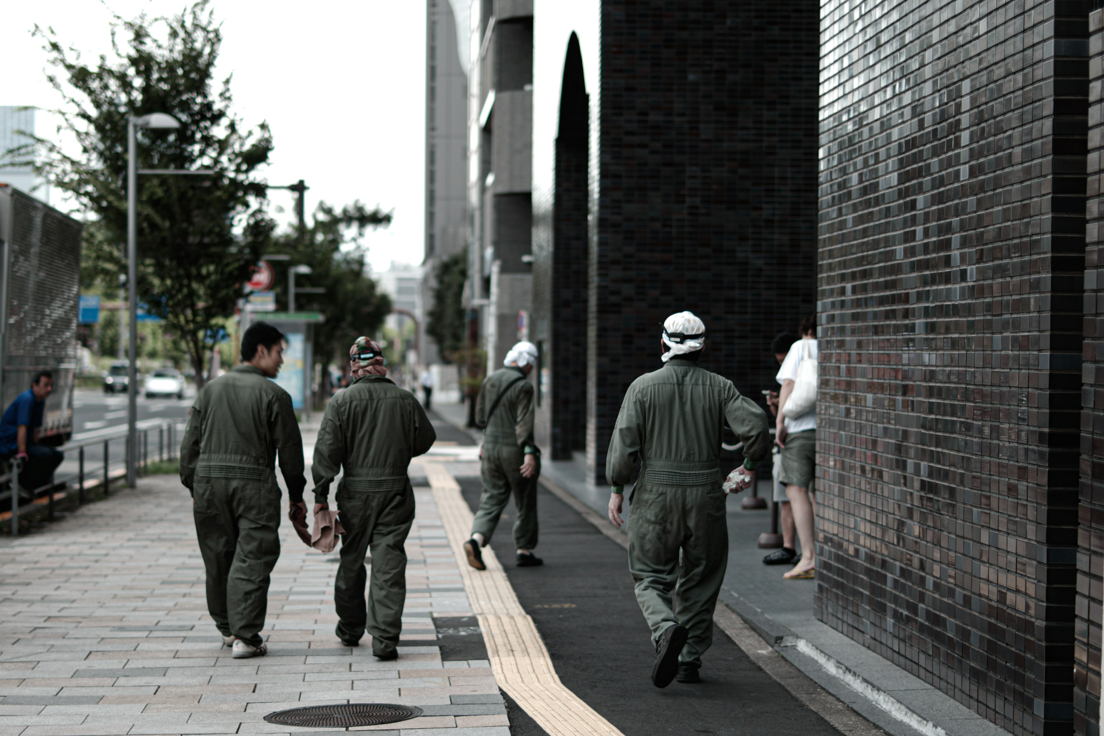 Varios hombres con uniformes de trabajo caminando en un entorno urbano