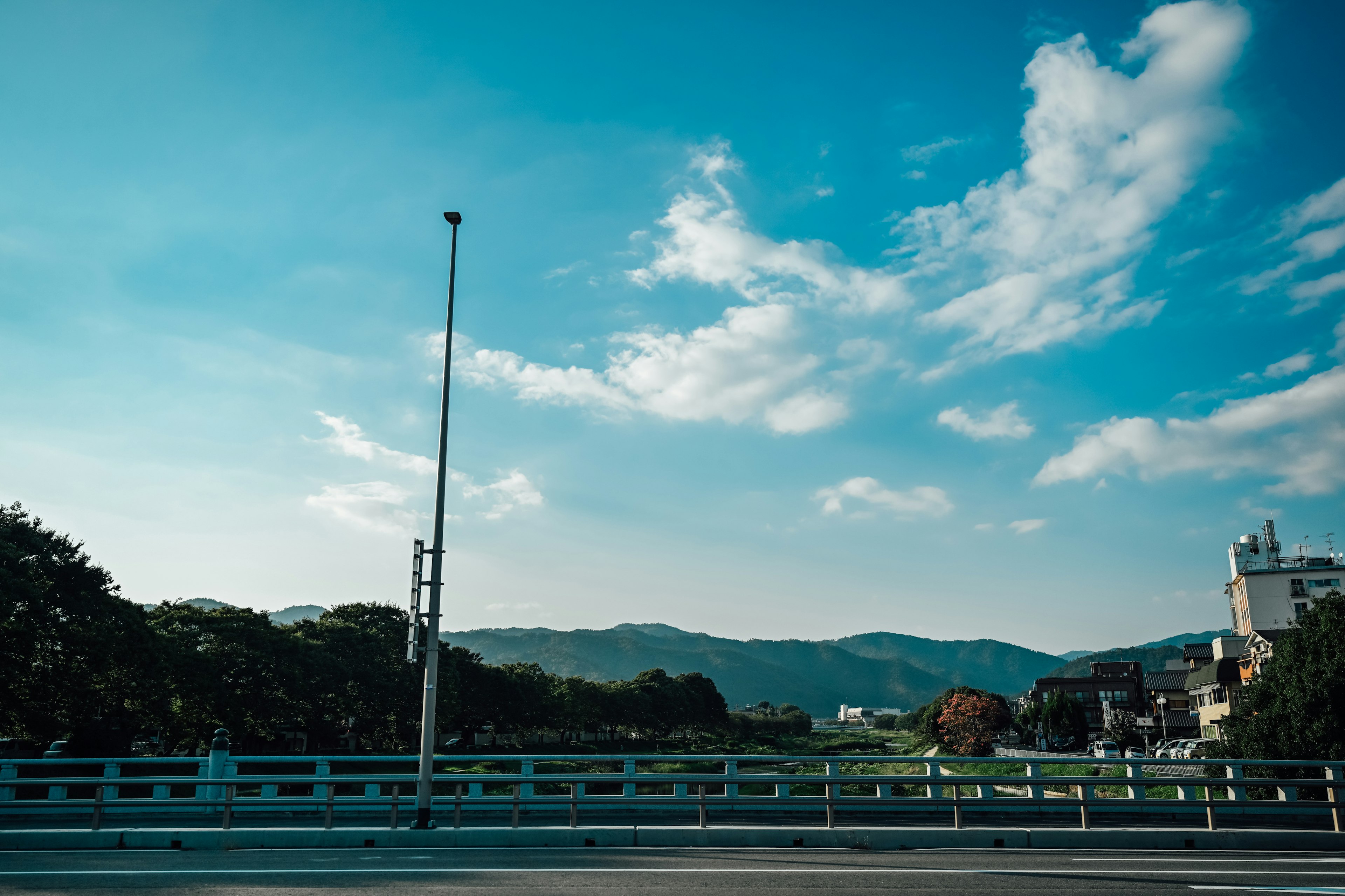 Scenic view of mountains and river under blue sky with white clouds