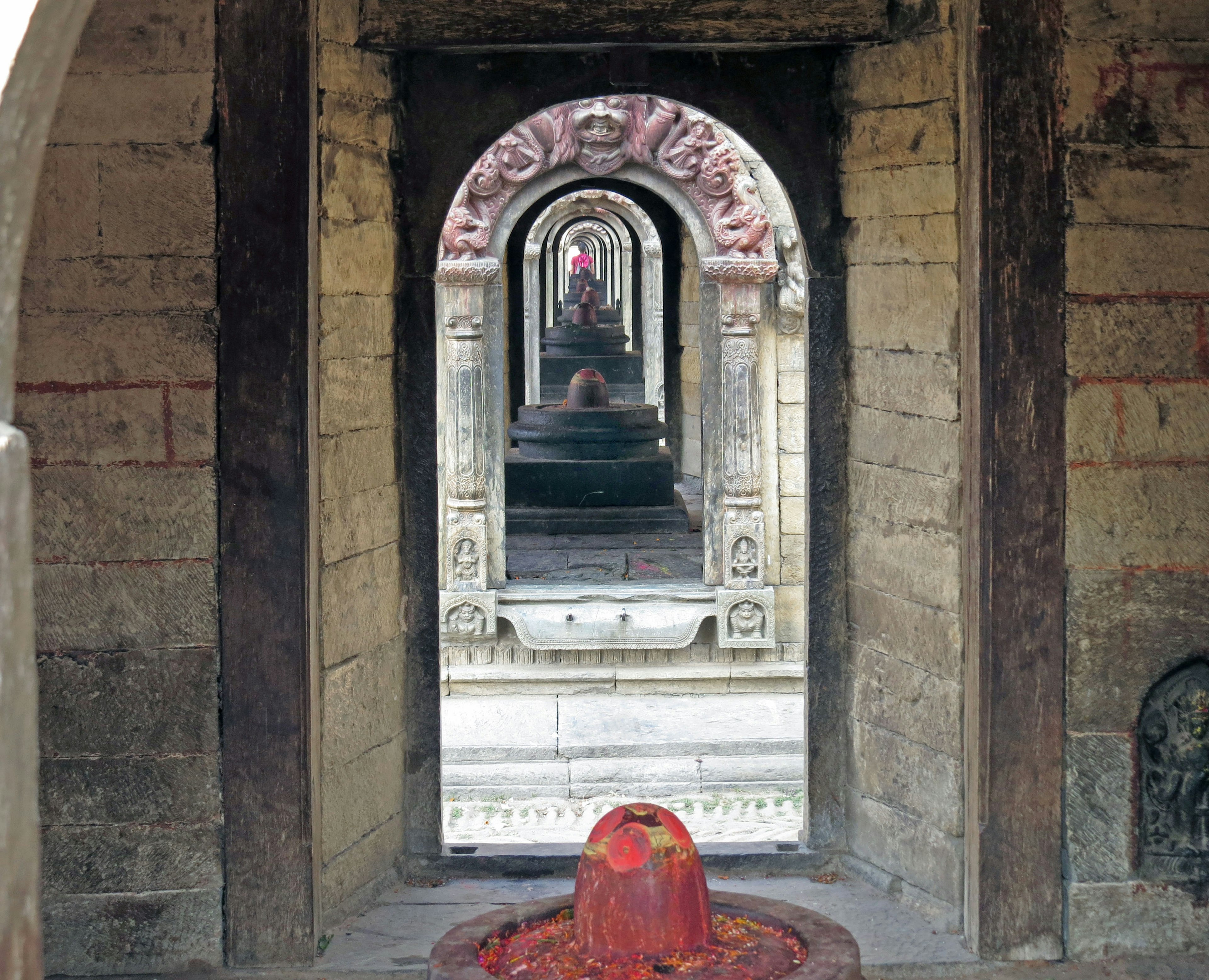 Blick auf geschnitzte Bögen und Shiva-Lingam-Statuen in einem Tempel