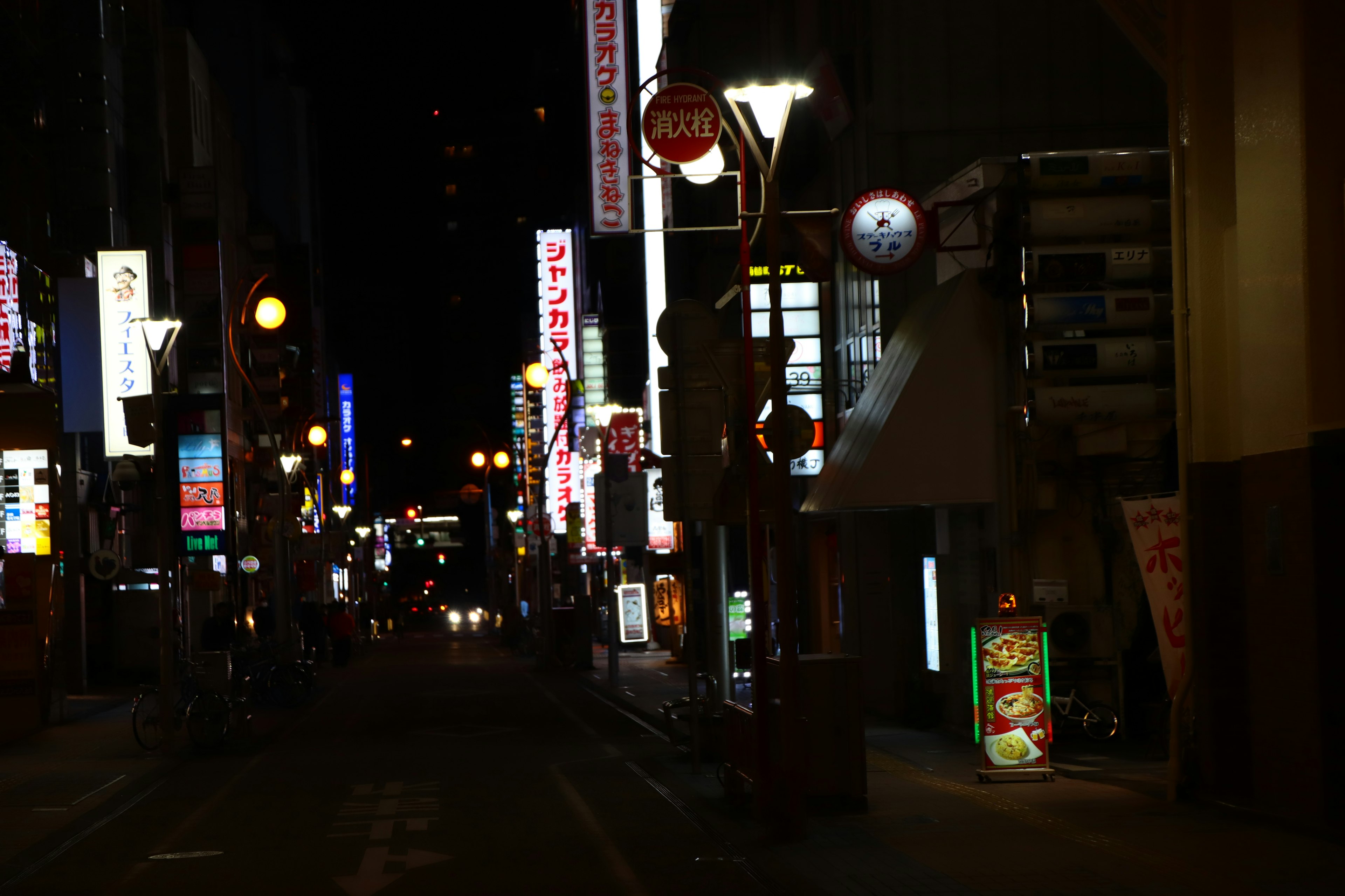 Scena notturna di strada con insegne al neon e lampioni luminosi