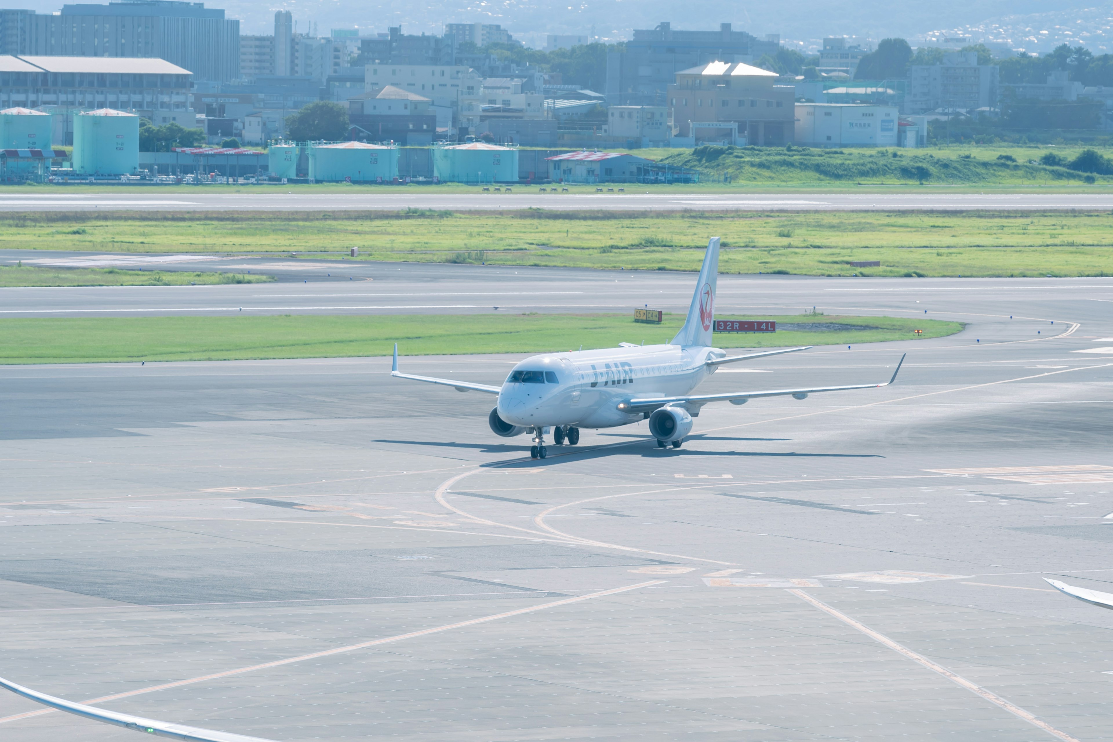 Small aircraft taxiing on runway with city skyline in background