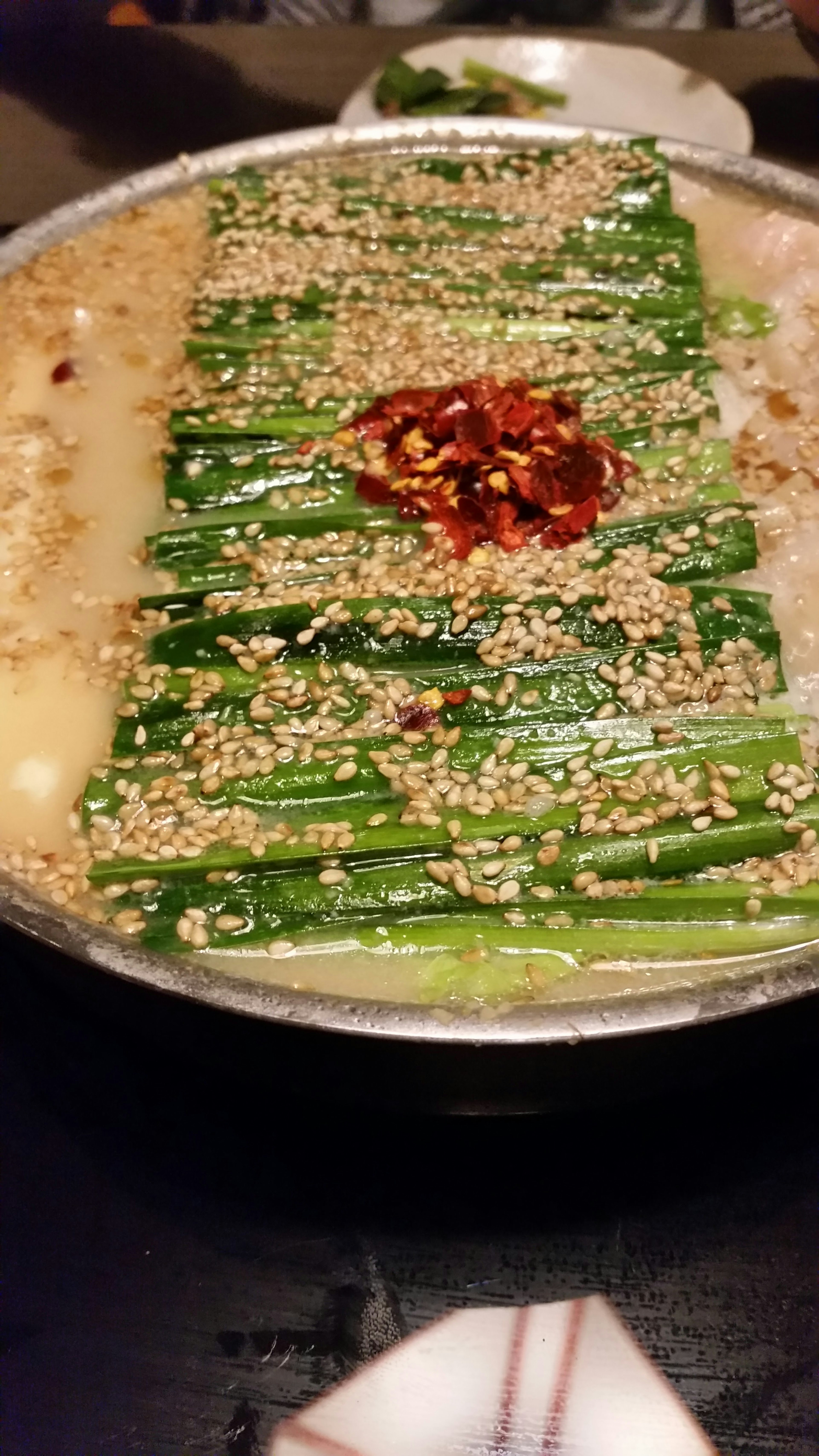 Un piatto di zuppa con verdure verdi guarnito con semi di sesamo e peperoncino