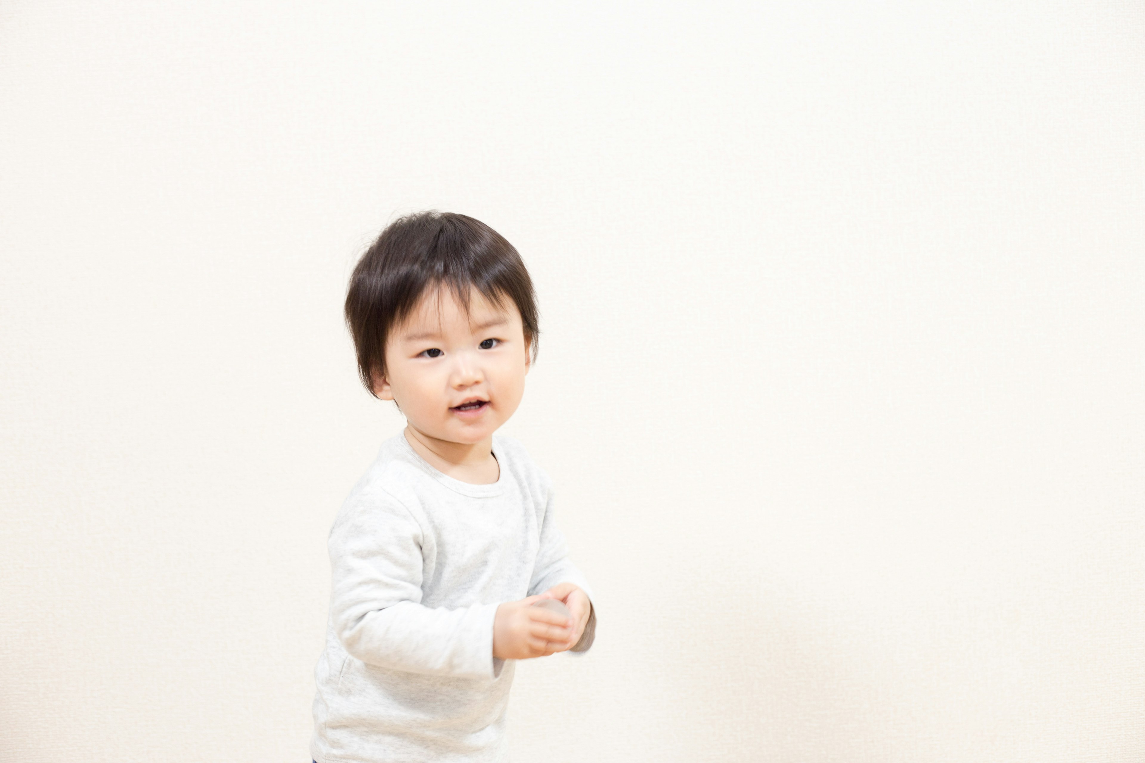 Toddler smiling while playing against a white background