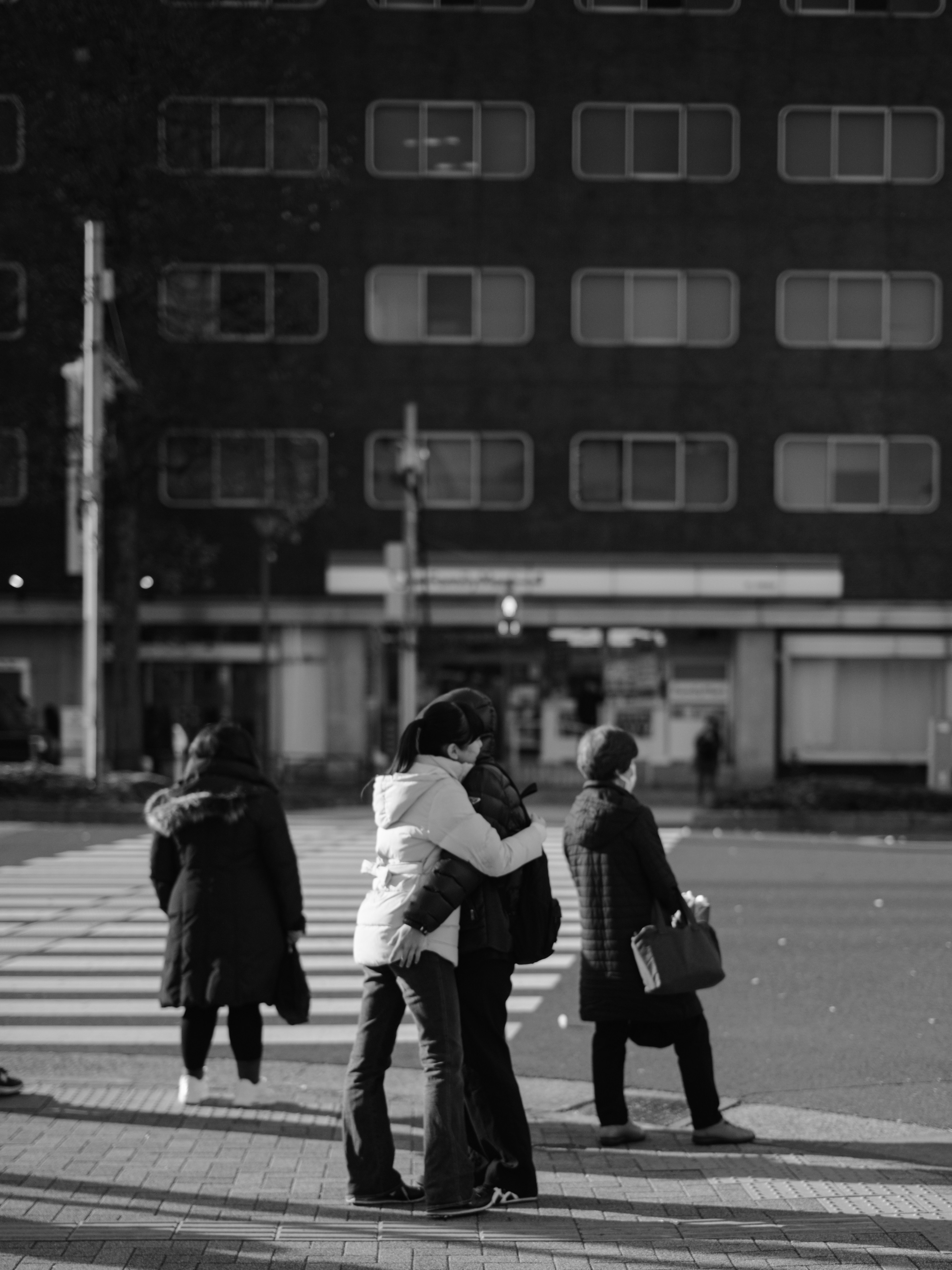 Couple embracing at a crosswalk with pedestrians in the background