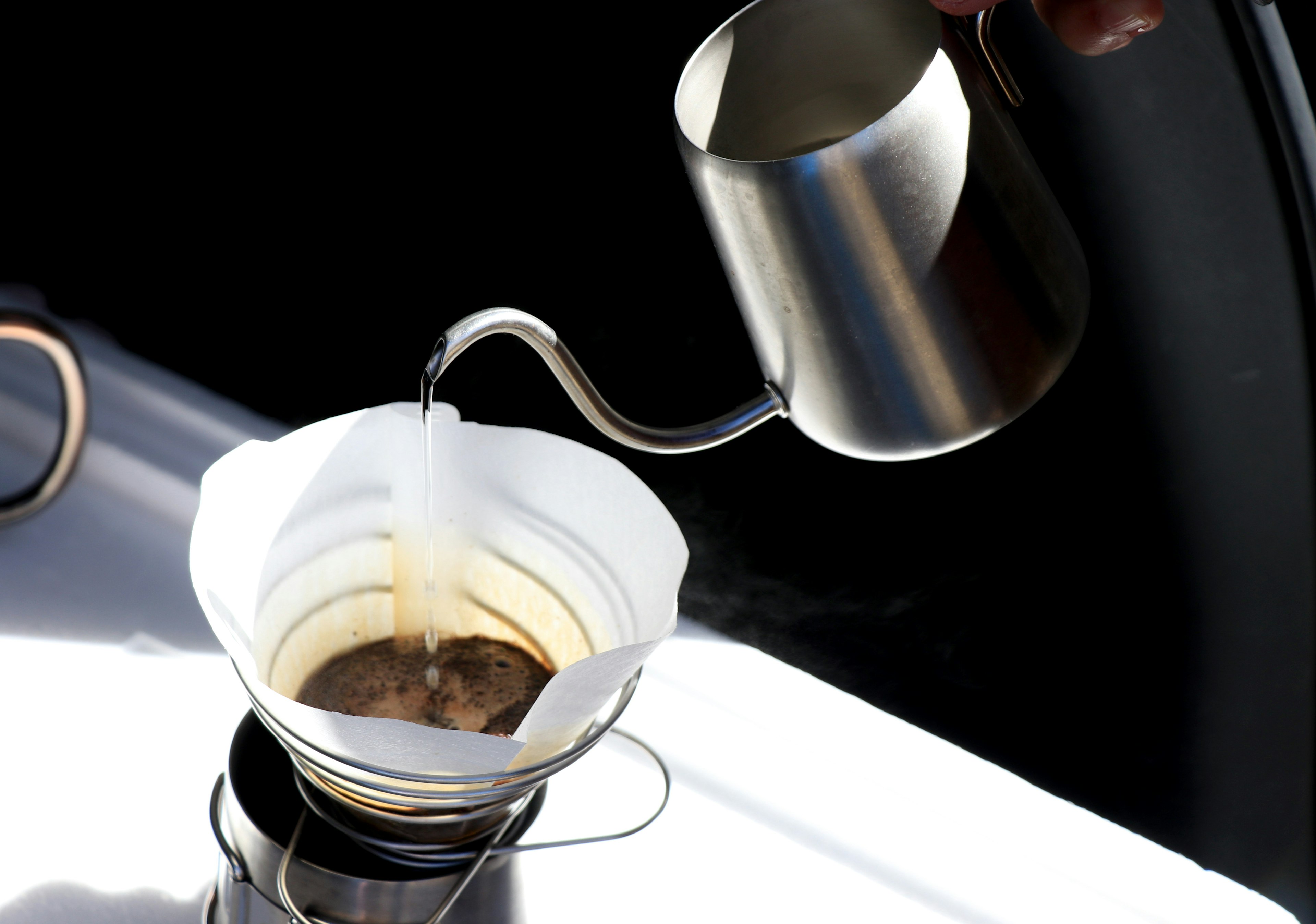 Pouring coffee into a filter with steam rising