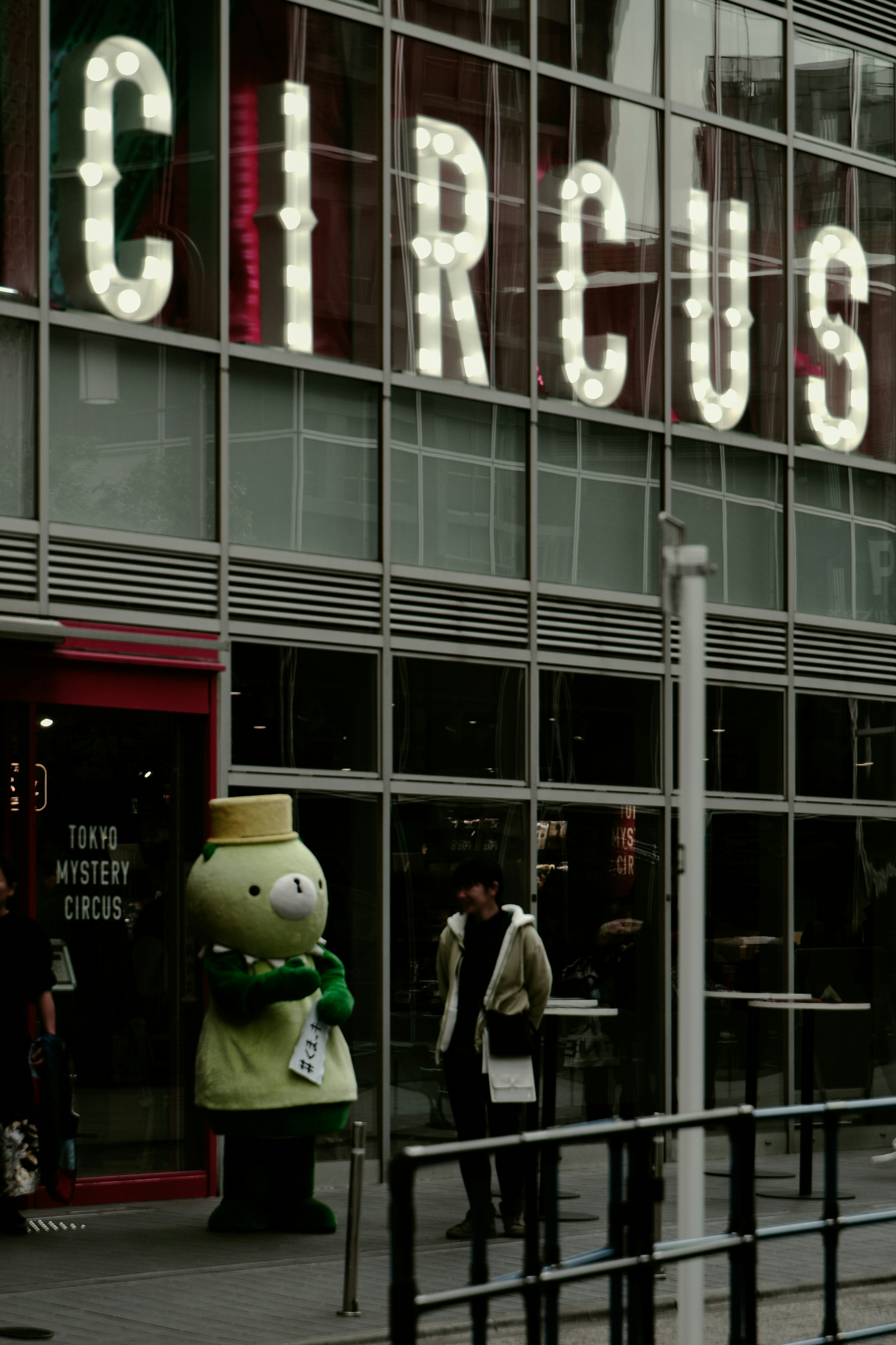 Character standing in front of a circus sign with people