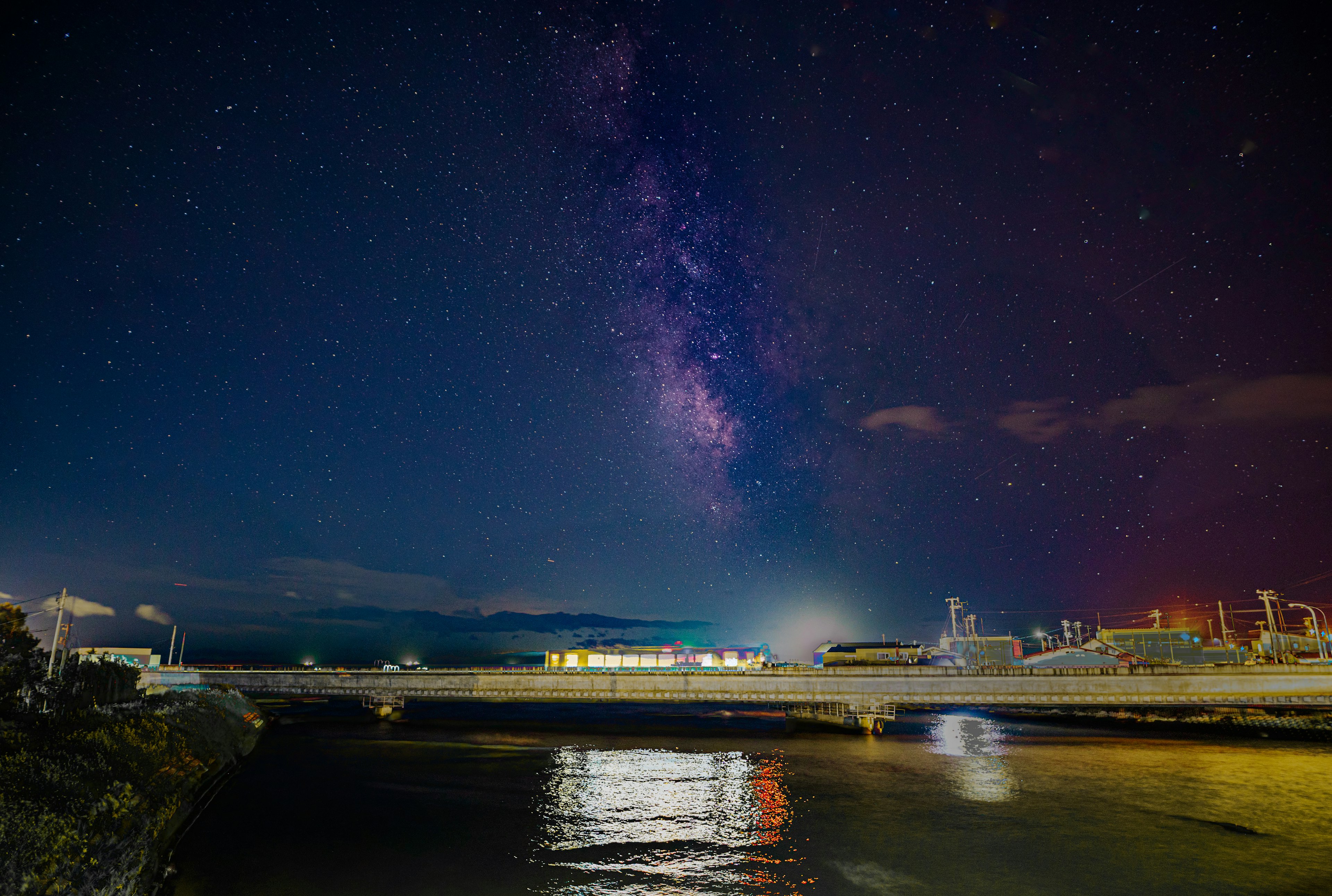 Vue panoramique d'une rivière et d'un pont sous un ciel étoilé avec la Voie lactée