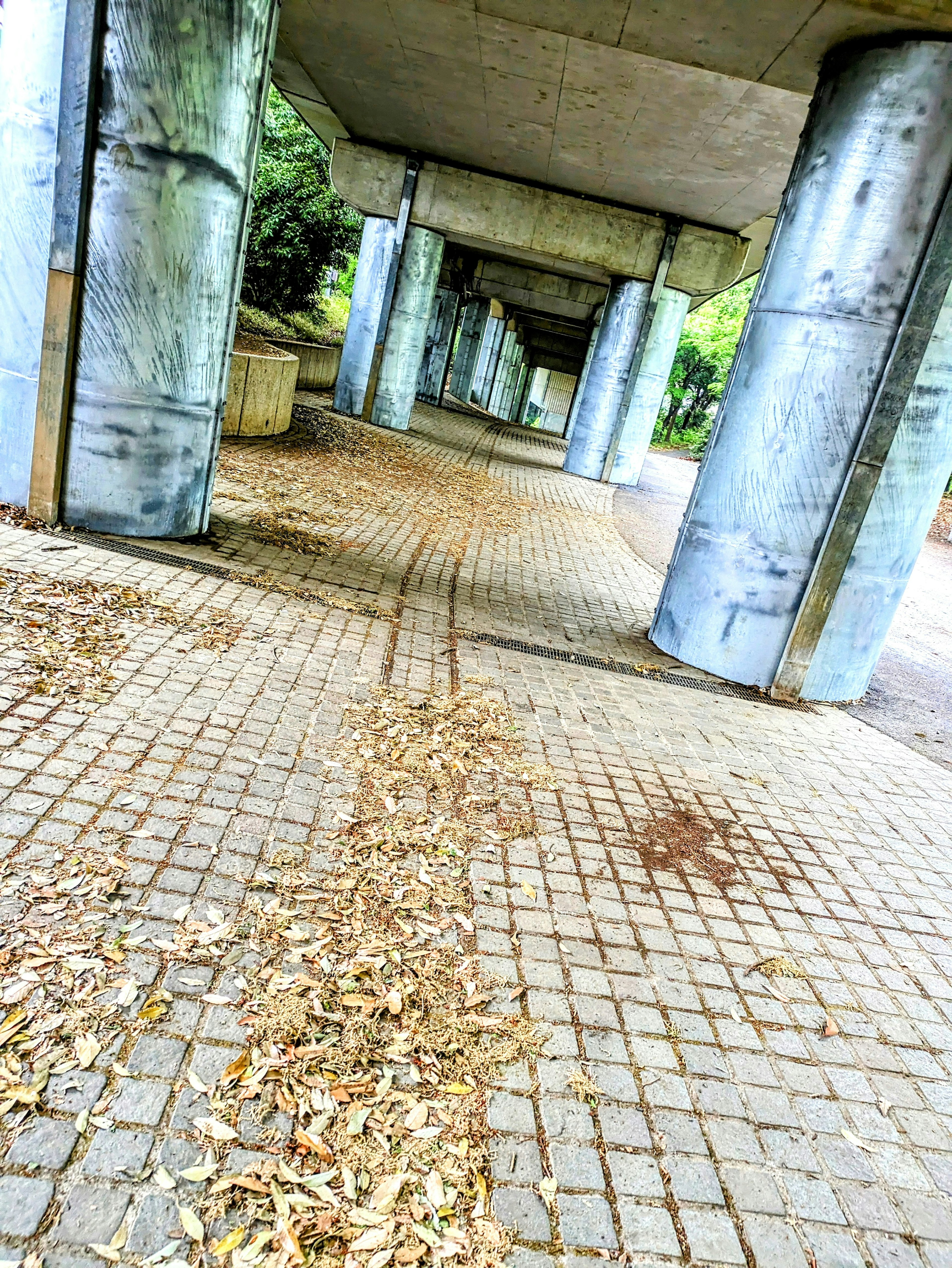 View of an arcade with concrete pillars and a brick pathway