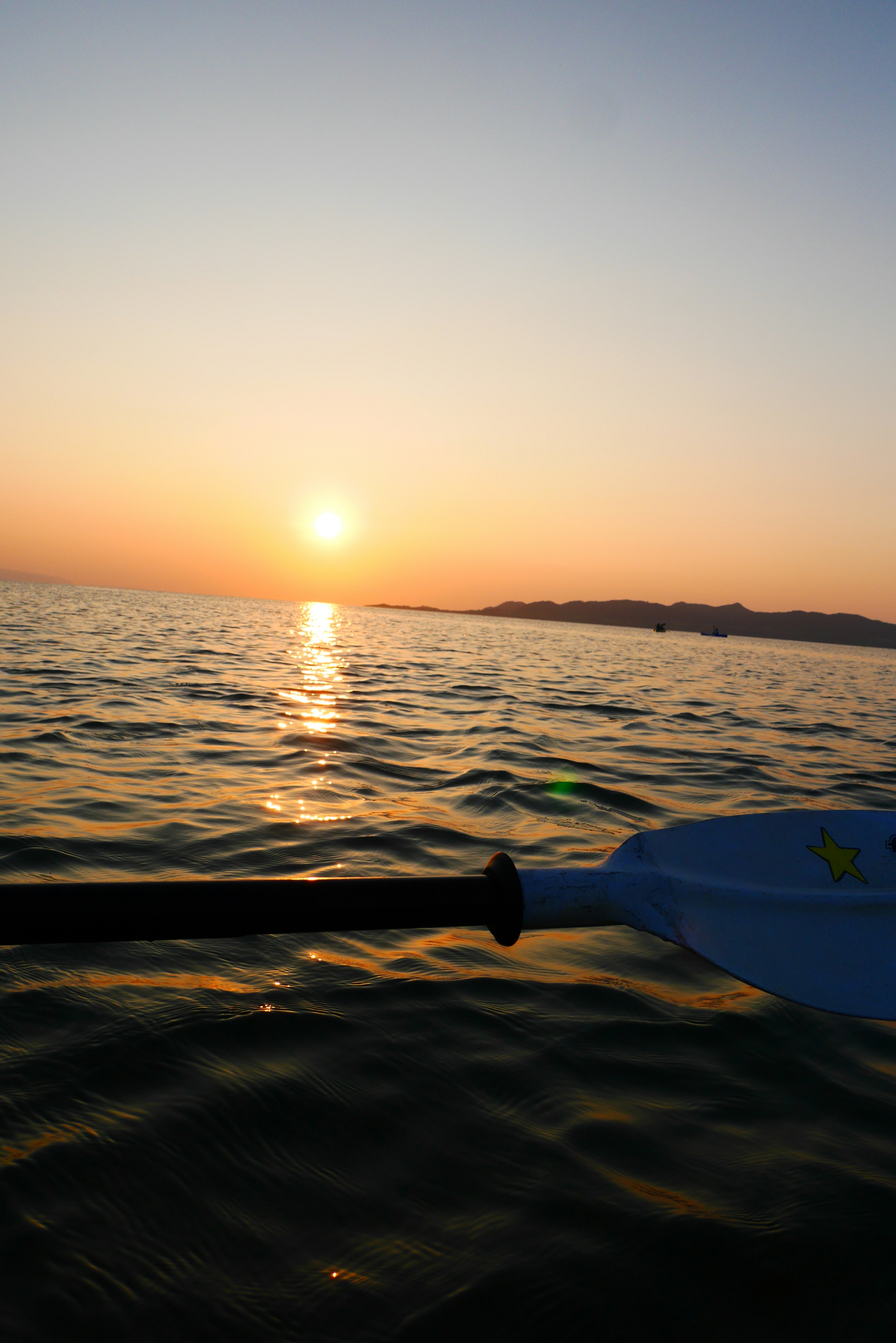 Sunset over the ocean with a boat paddle in view