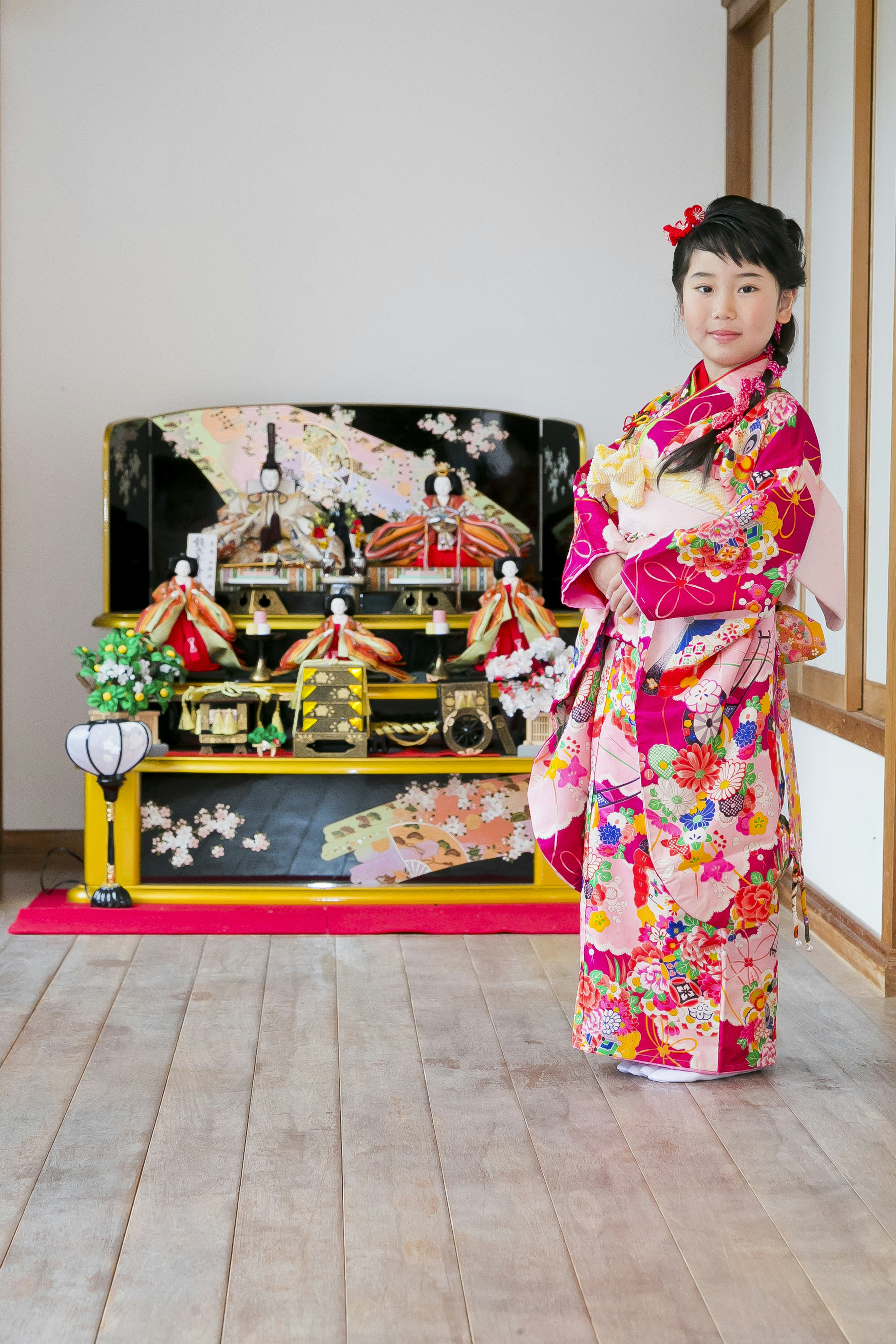 A girl in a kimono standing in front of traditional Japanese decorations