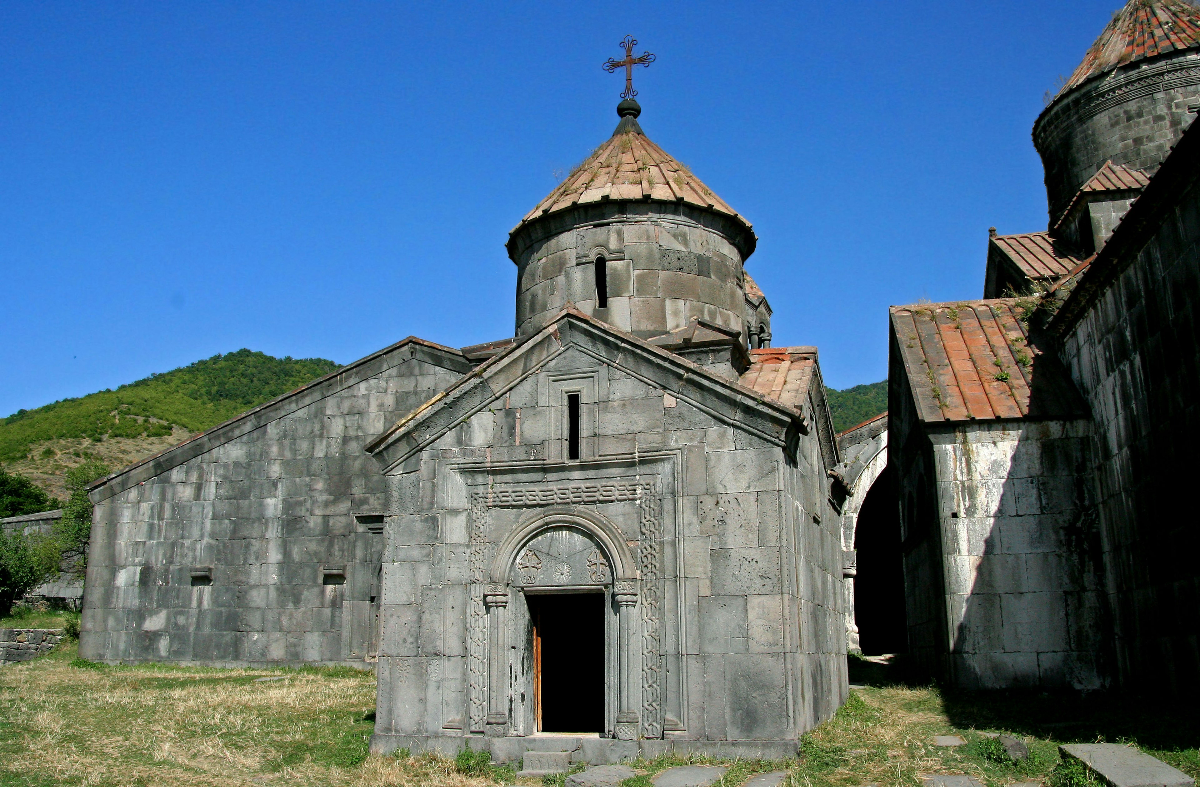 Ancien bâtiment d'église en pierre avec une croix et un ciel bleu