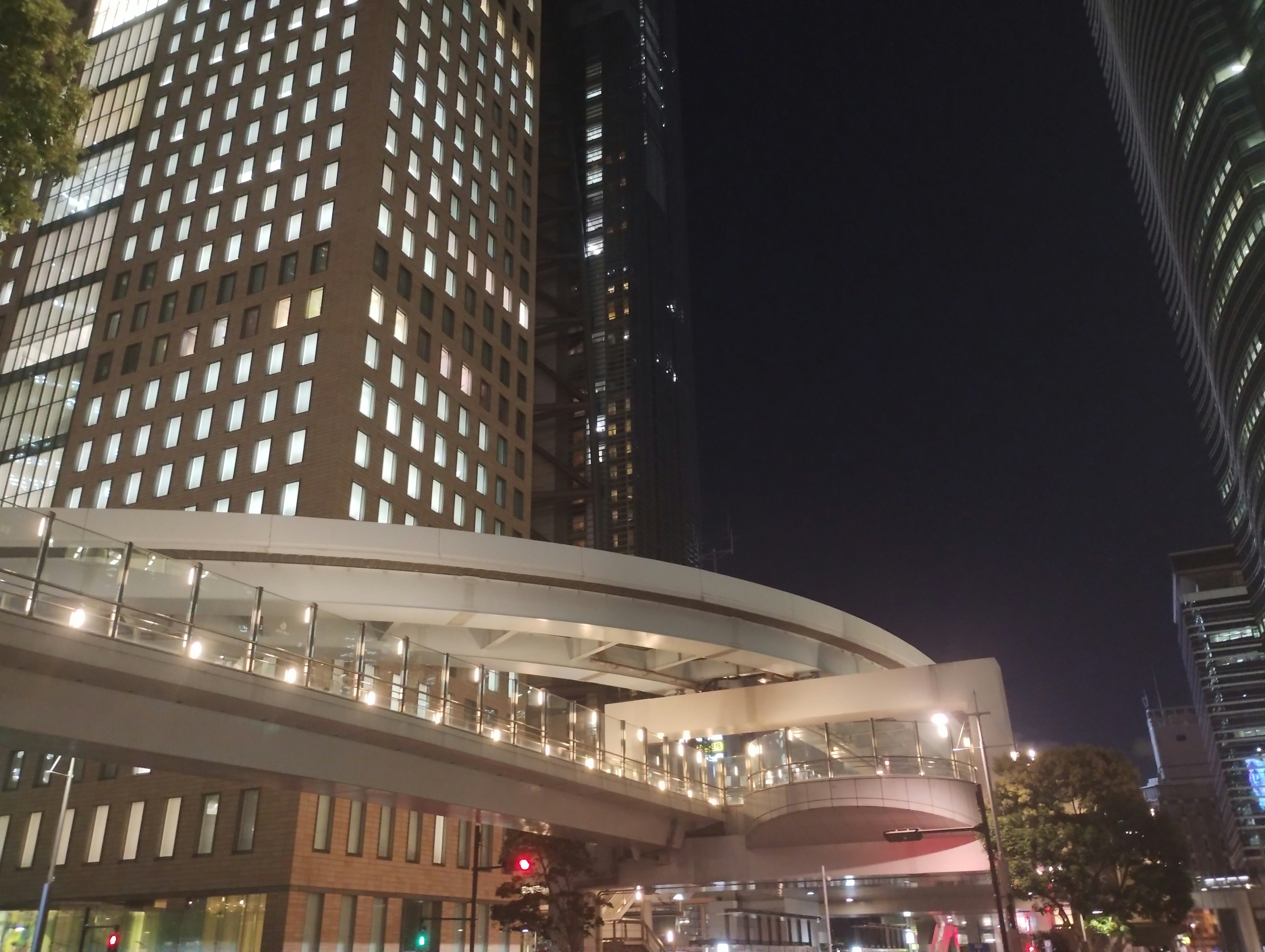 Edificios modernos y puente peatonal iluminado en un paisaje urbano nocturno