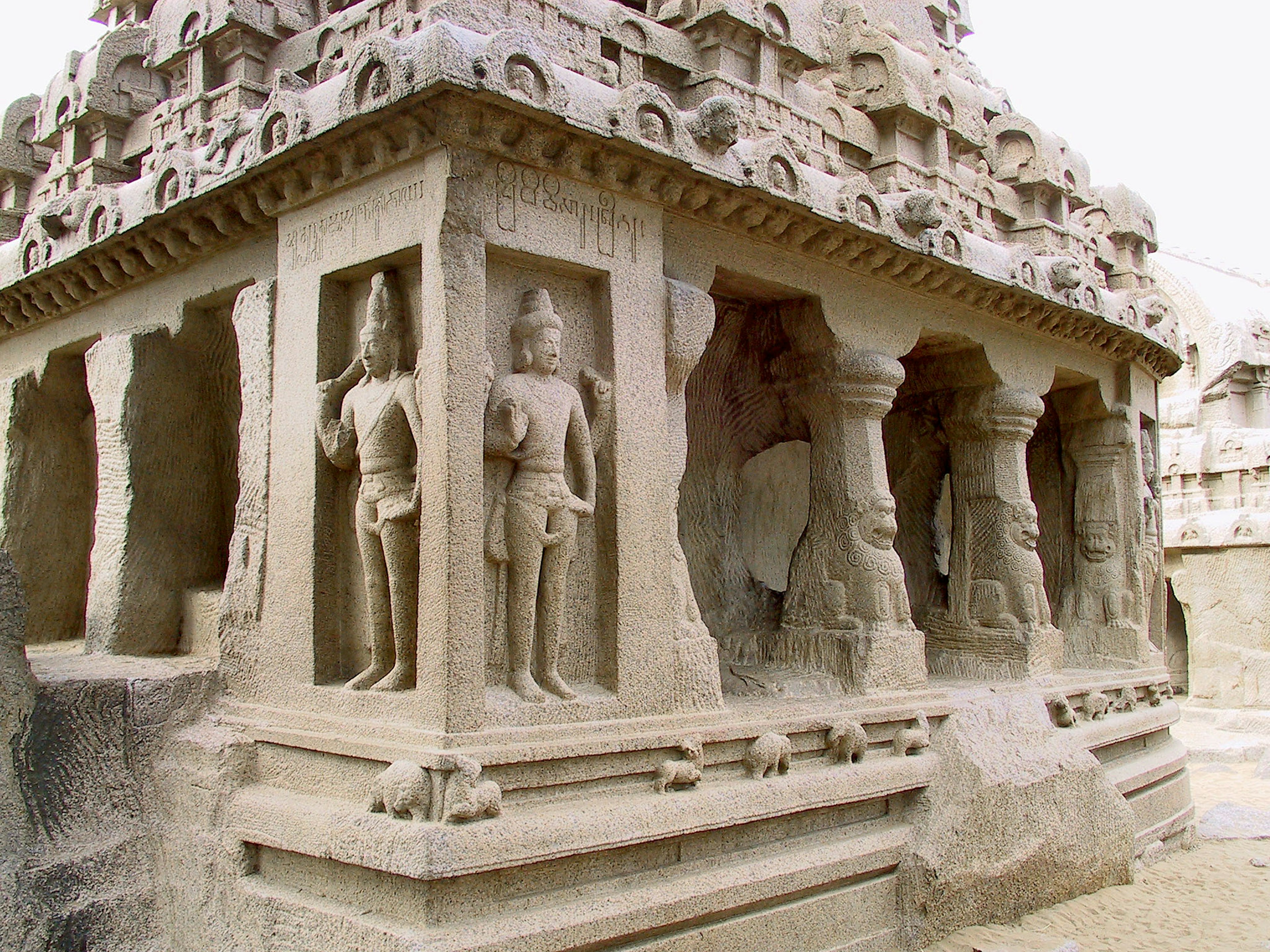 Ancient stone-carved temple featuring sculpted pillars and figures