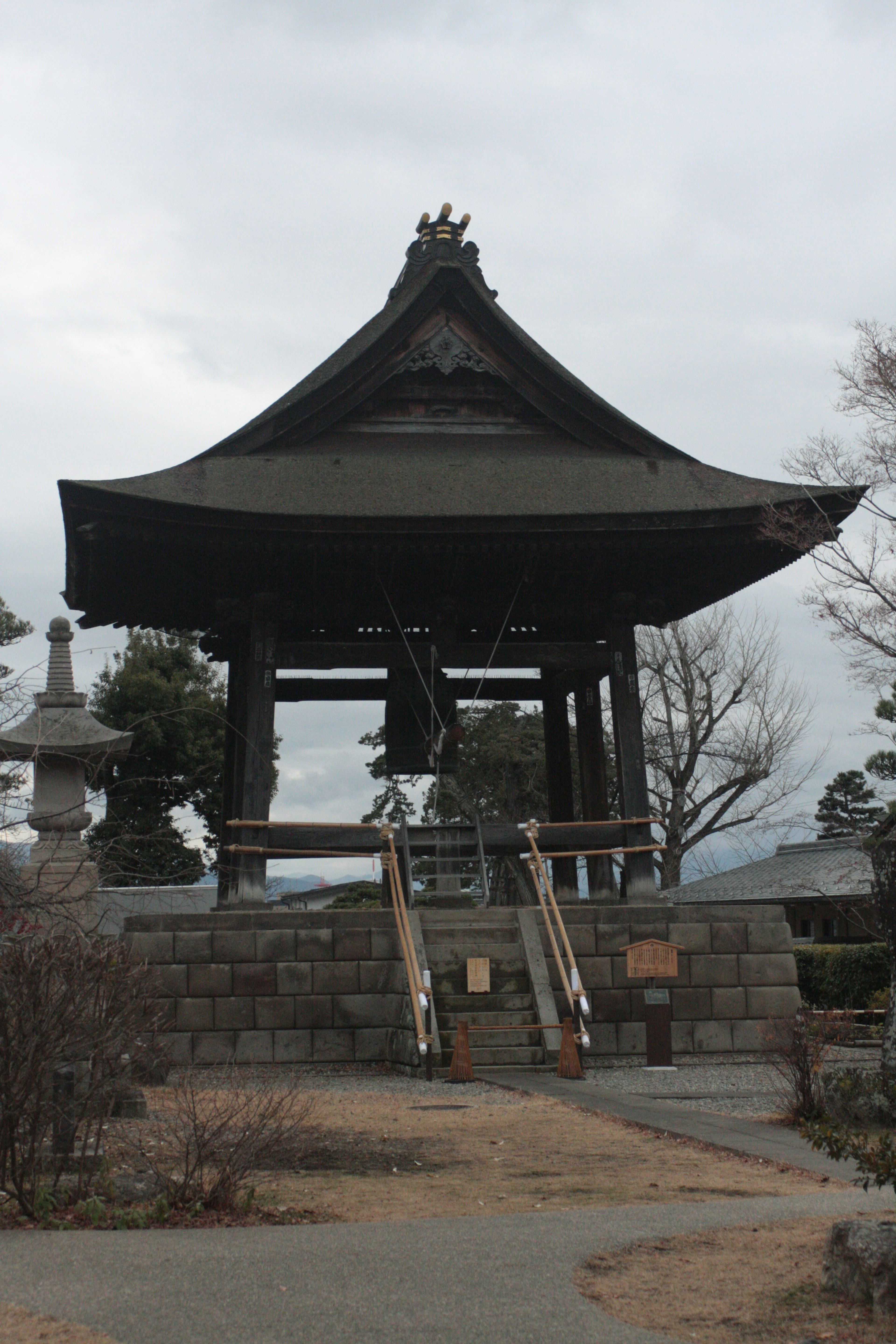 A serene temple scene featuring a black-roofed bell tower