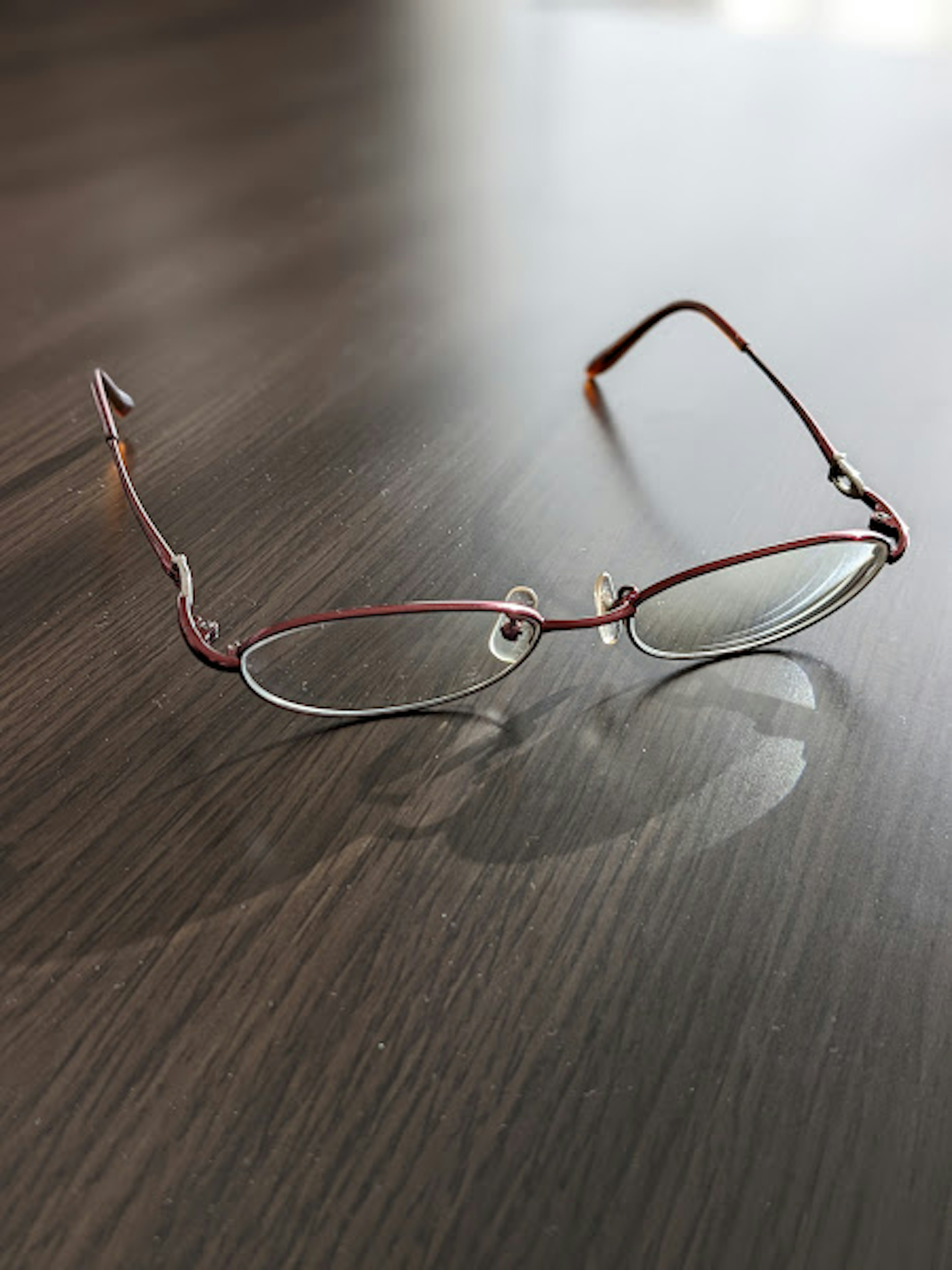 Gafas de montura roja descansando sobre una mesa de madera