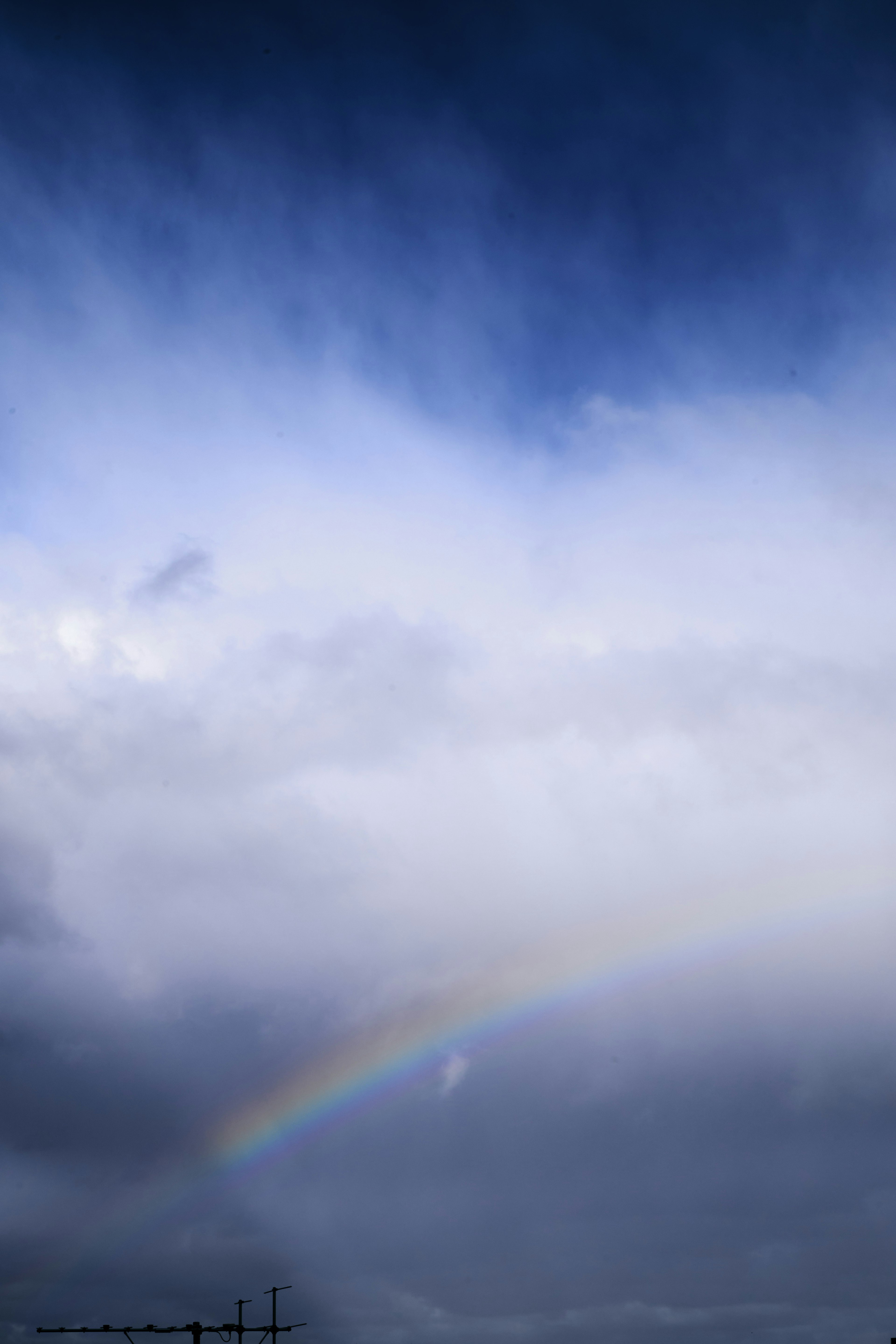 青い空と雲の間に虹がかかっている風景