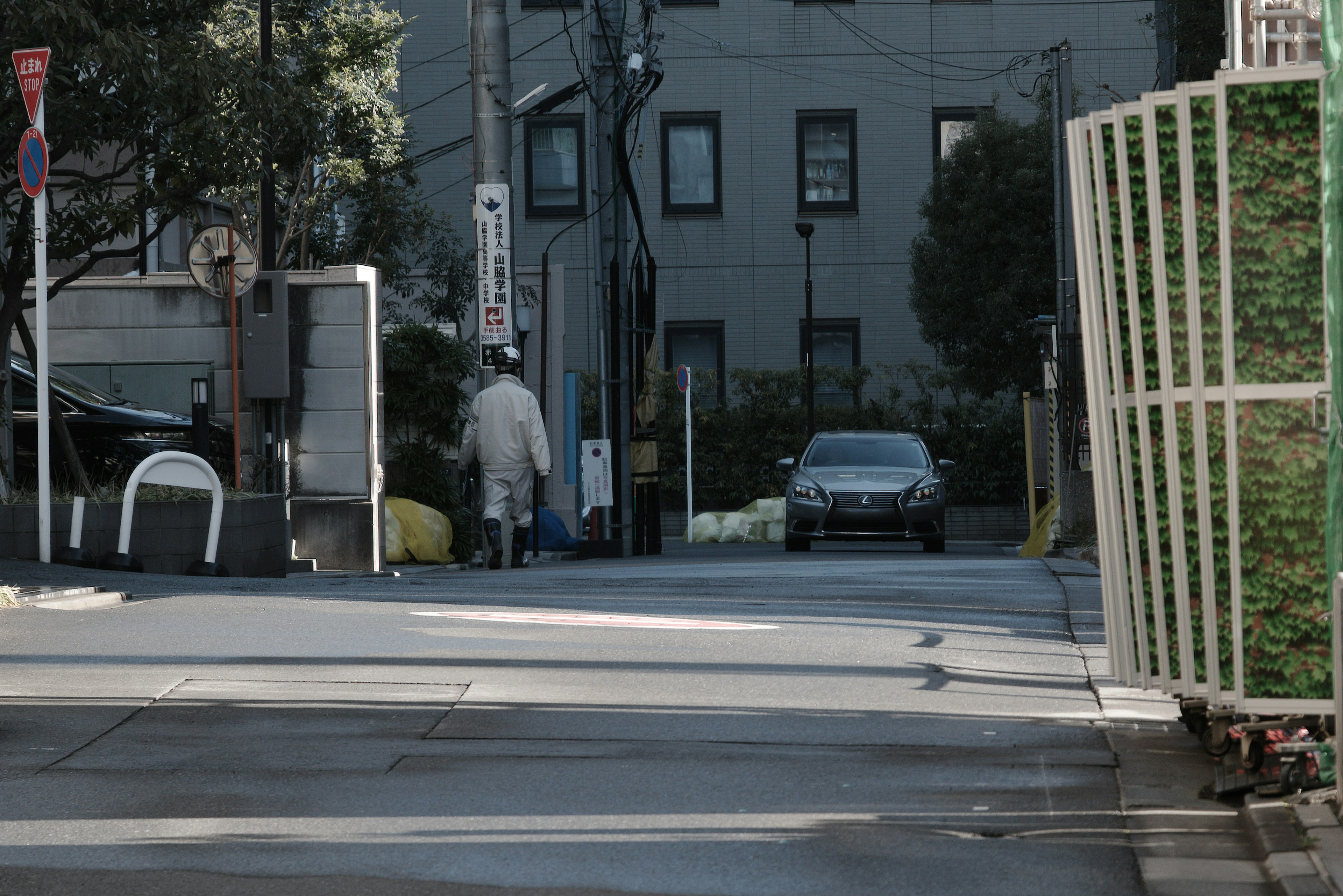 Quiet street corner scene with parked car and green fence