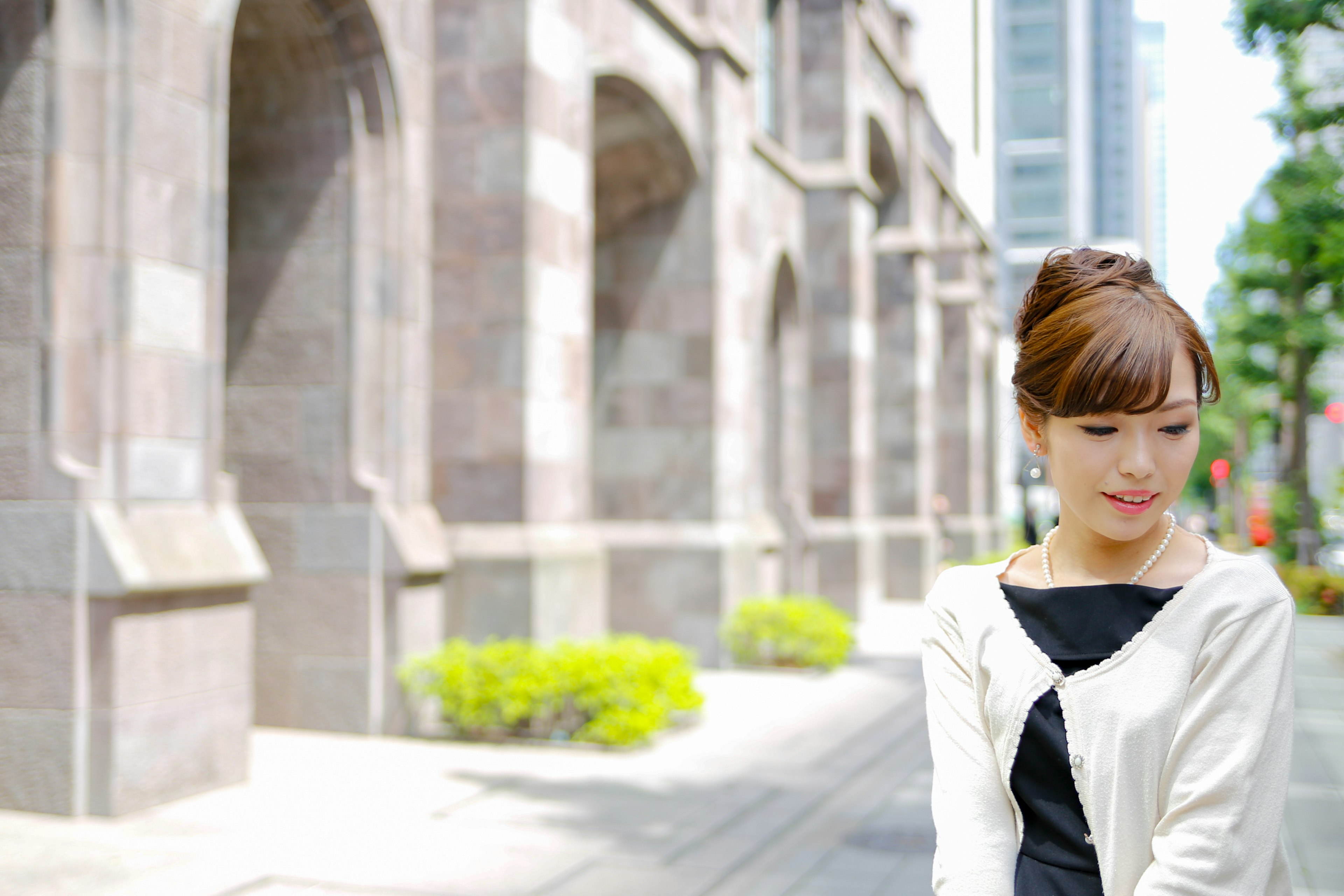 A woman smiling in the city with modern buildings and classical architecture in the background