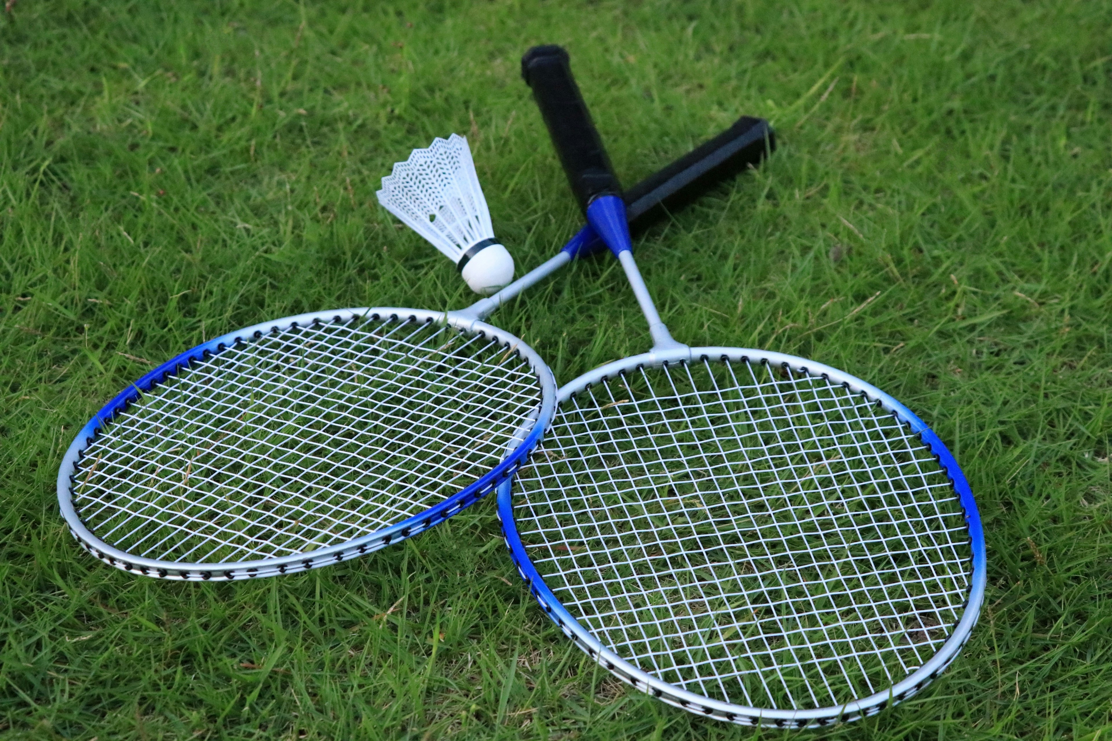 Two badminton rackets and a shuttlecock resting on green grass