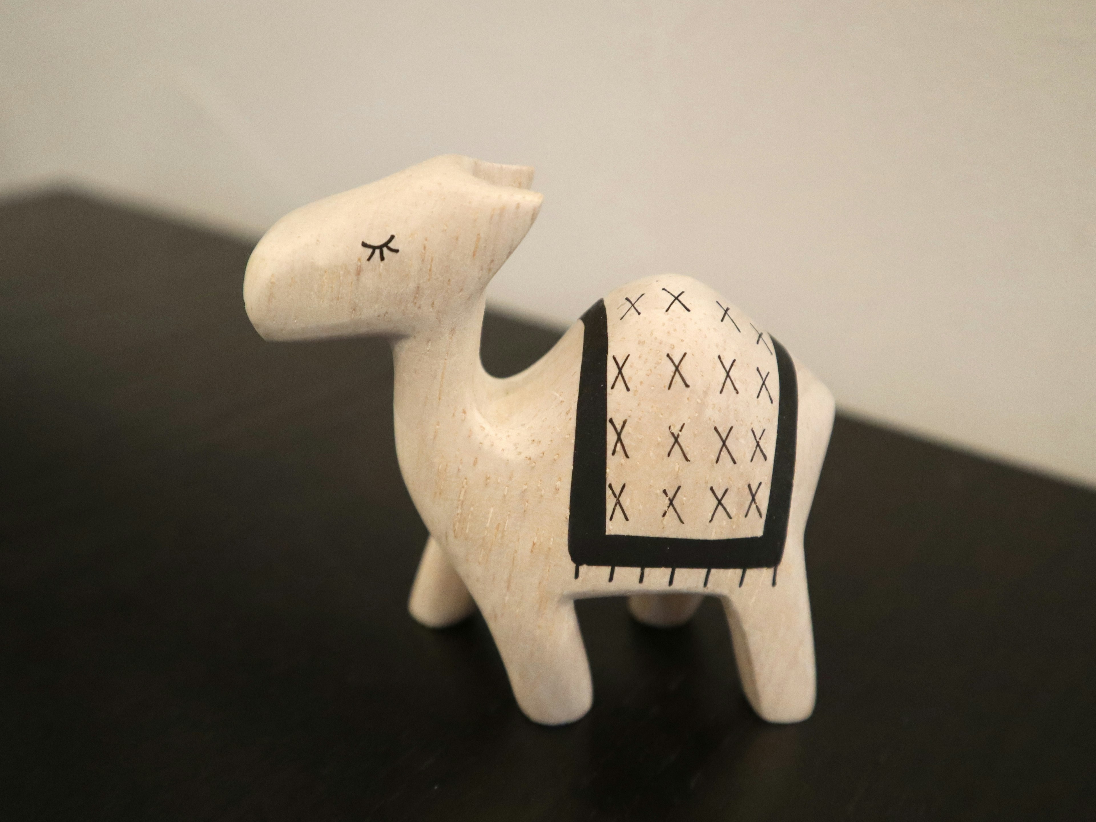 Figurita de camello de madera blanca con silla de montar de patrón negro