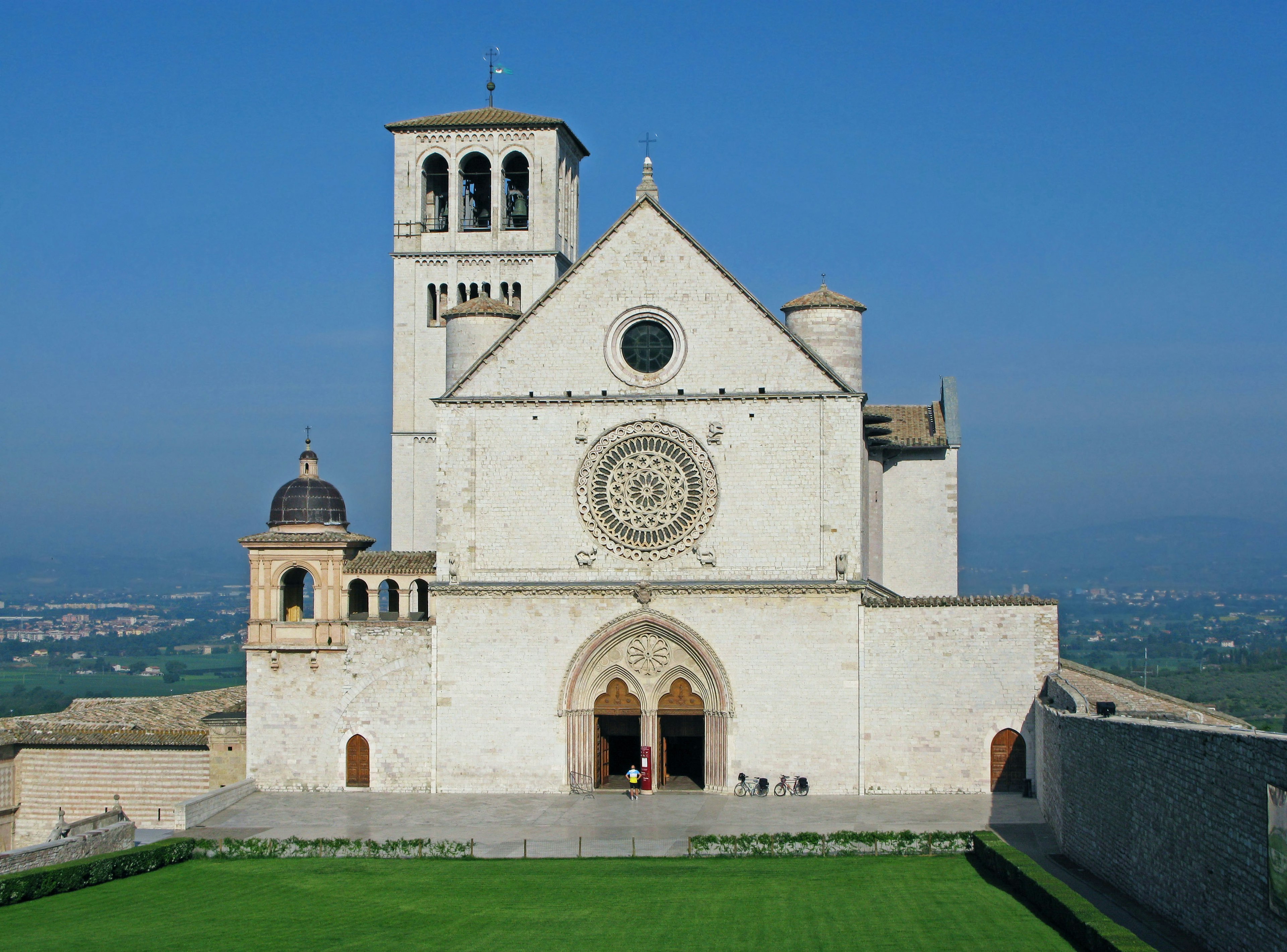 Außenansicht der Basilika San Francesco in Assisi unter einem klaren blauen Himmel