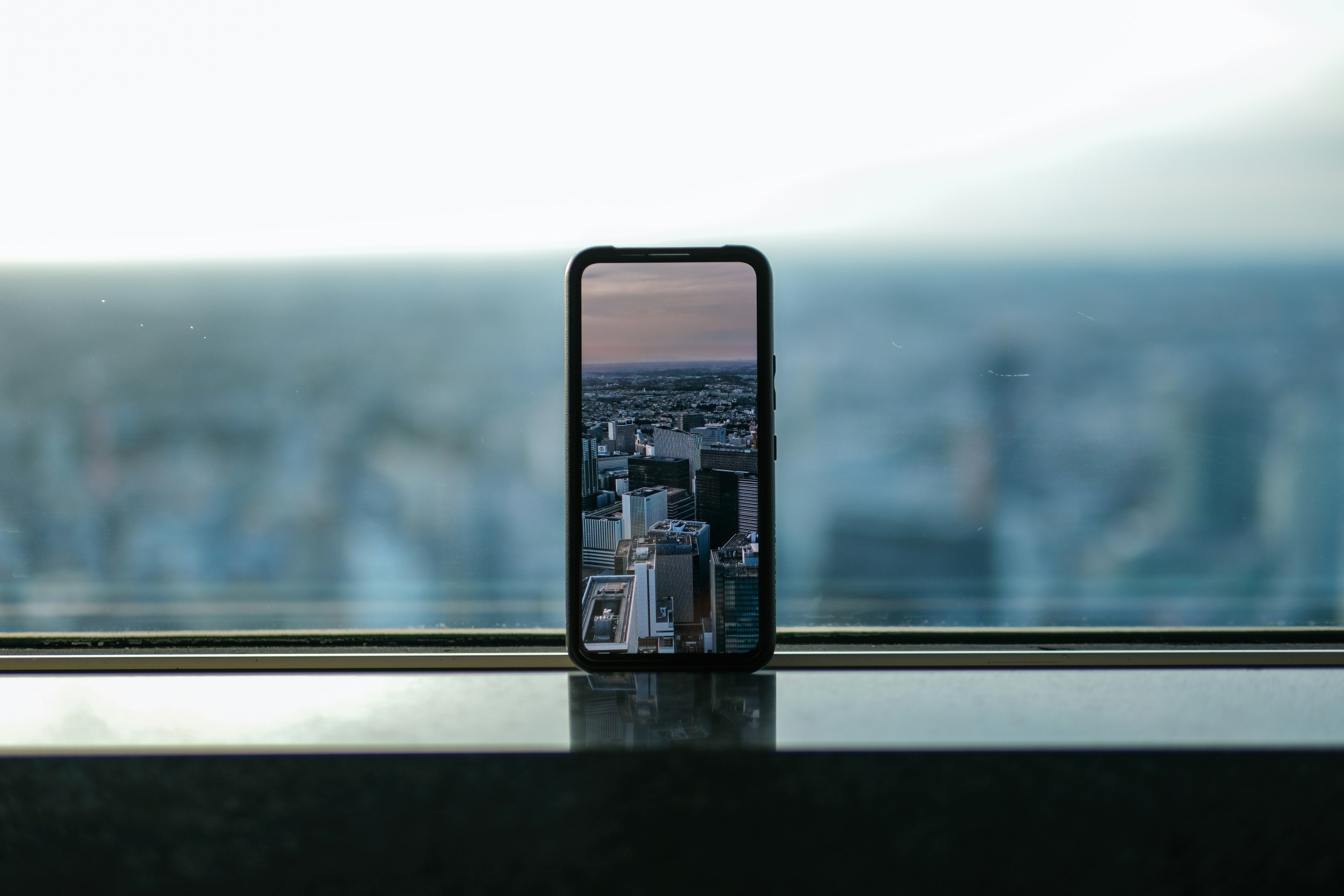 窓際に置かれたスマートフォンが都市の景色を映し出している
