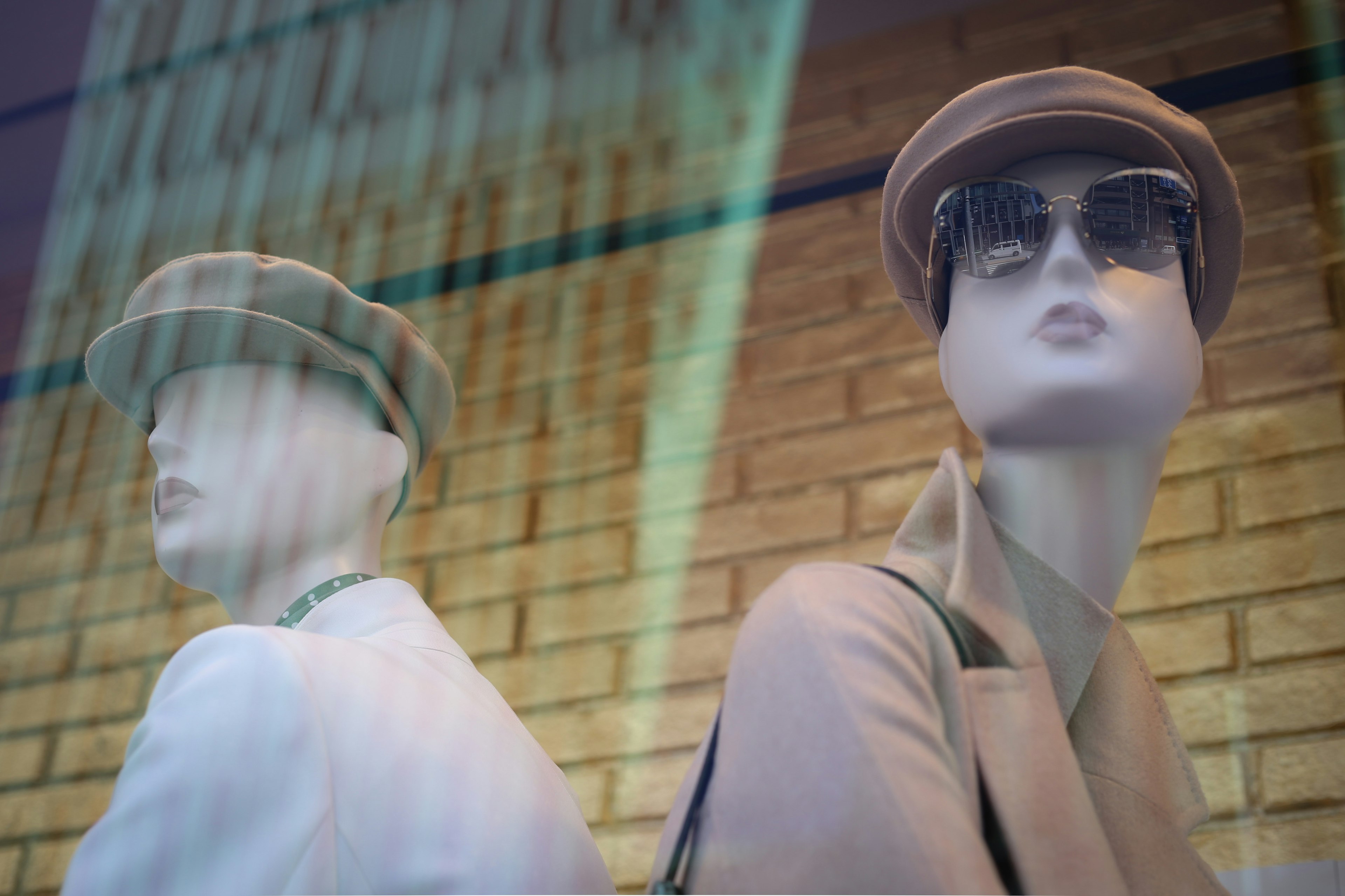 Two mannequins showcasing fashion in stylish hats and sunglasses