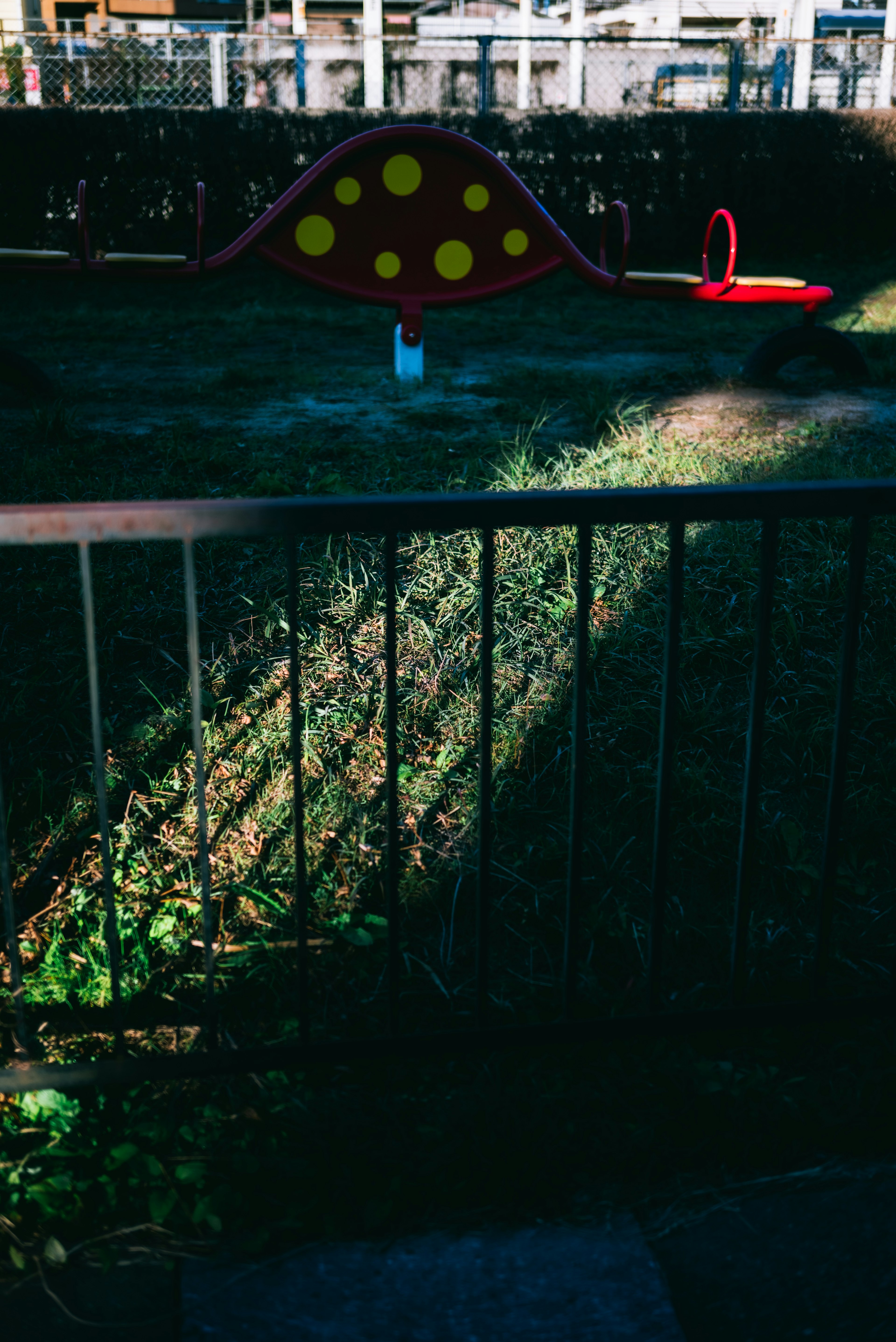 Una esquina de parque con un tobogán rojo y una estructura de lunares amarillos