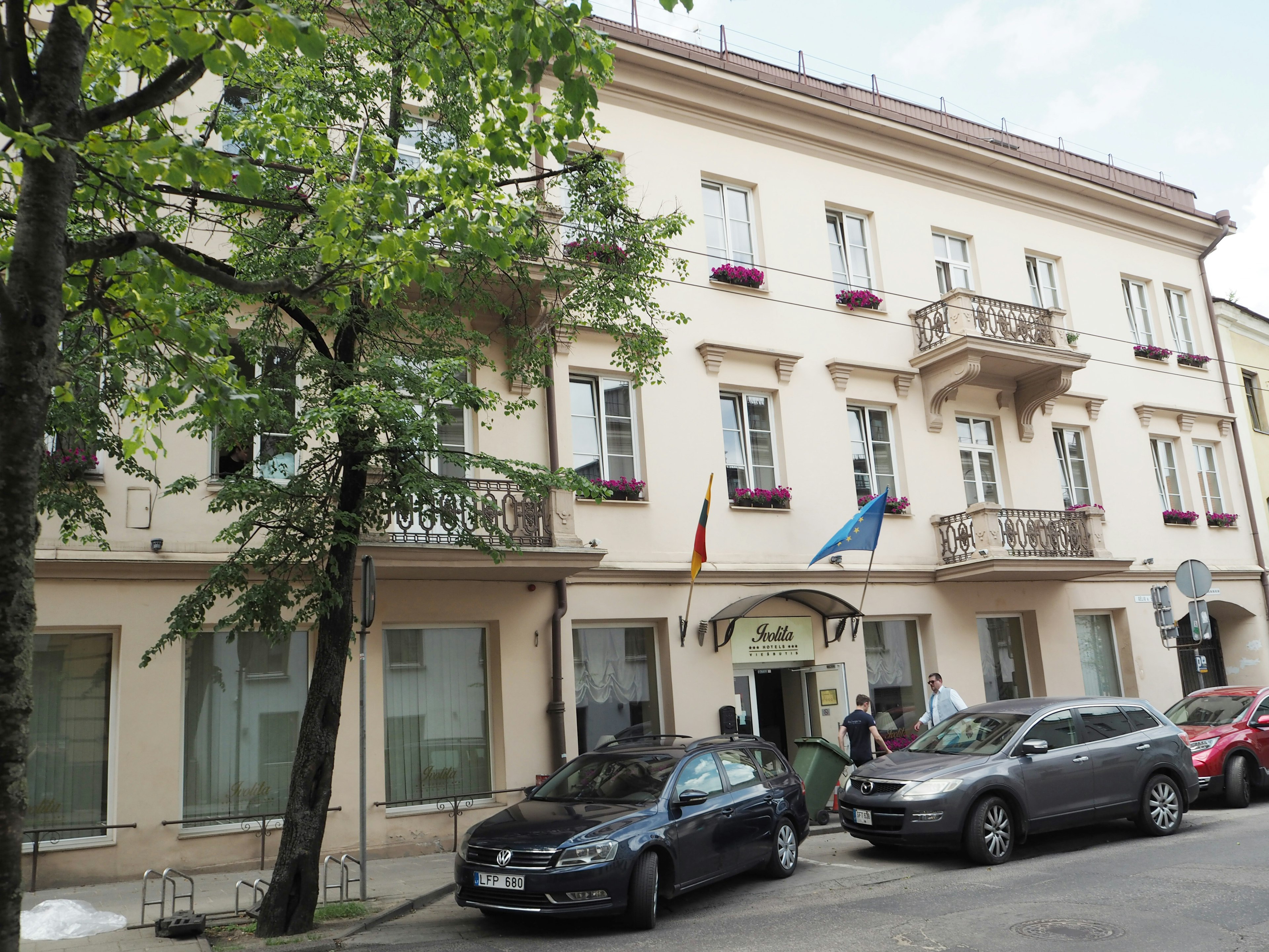 Edificio elegante con balcones y flores árboles a lo largo de la calle