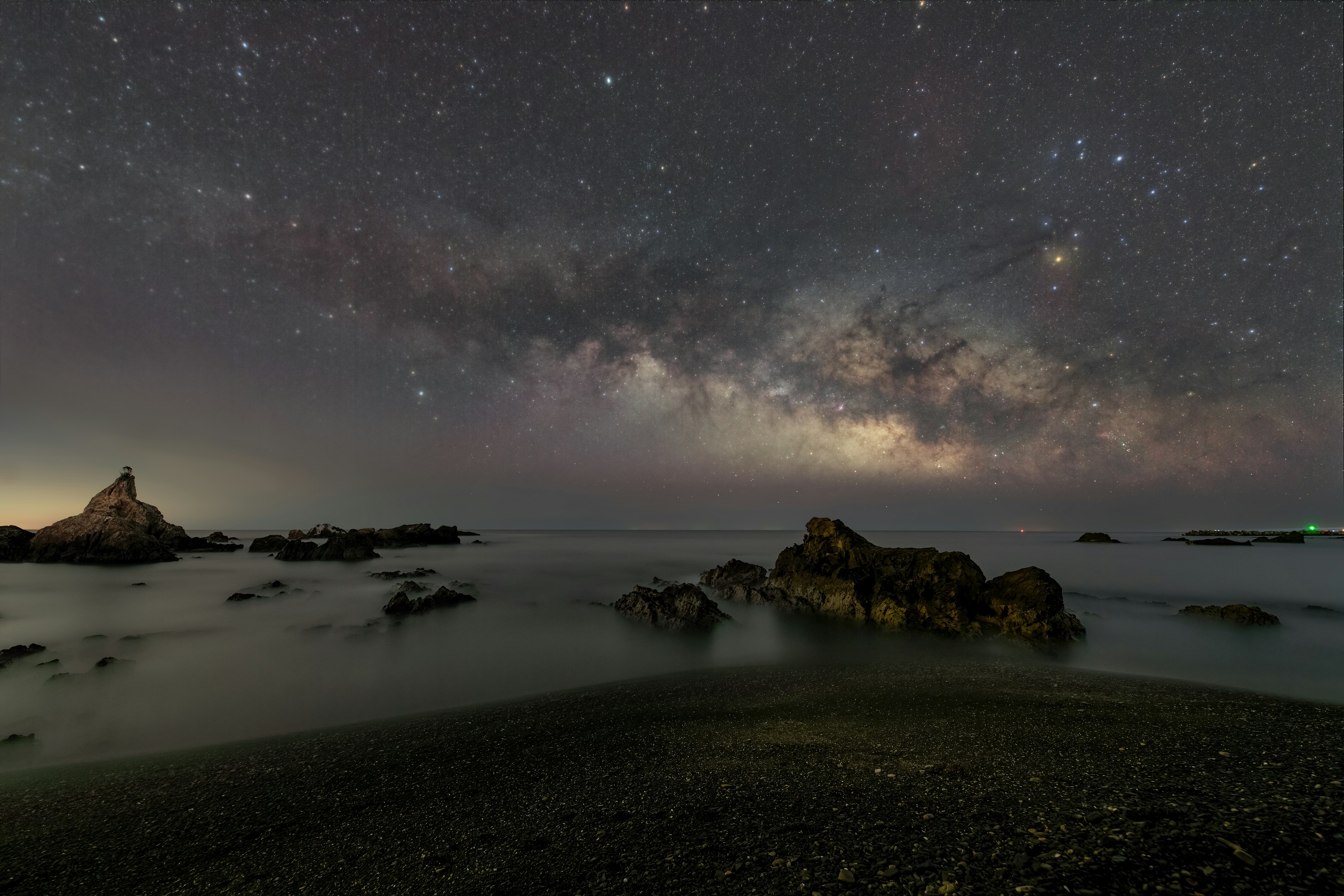 Ciel nocturne spectaculaire avec la Voie lactée sur une plage tranquille et une côte rocheuse