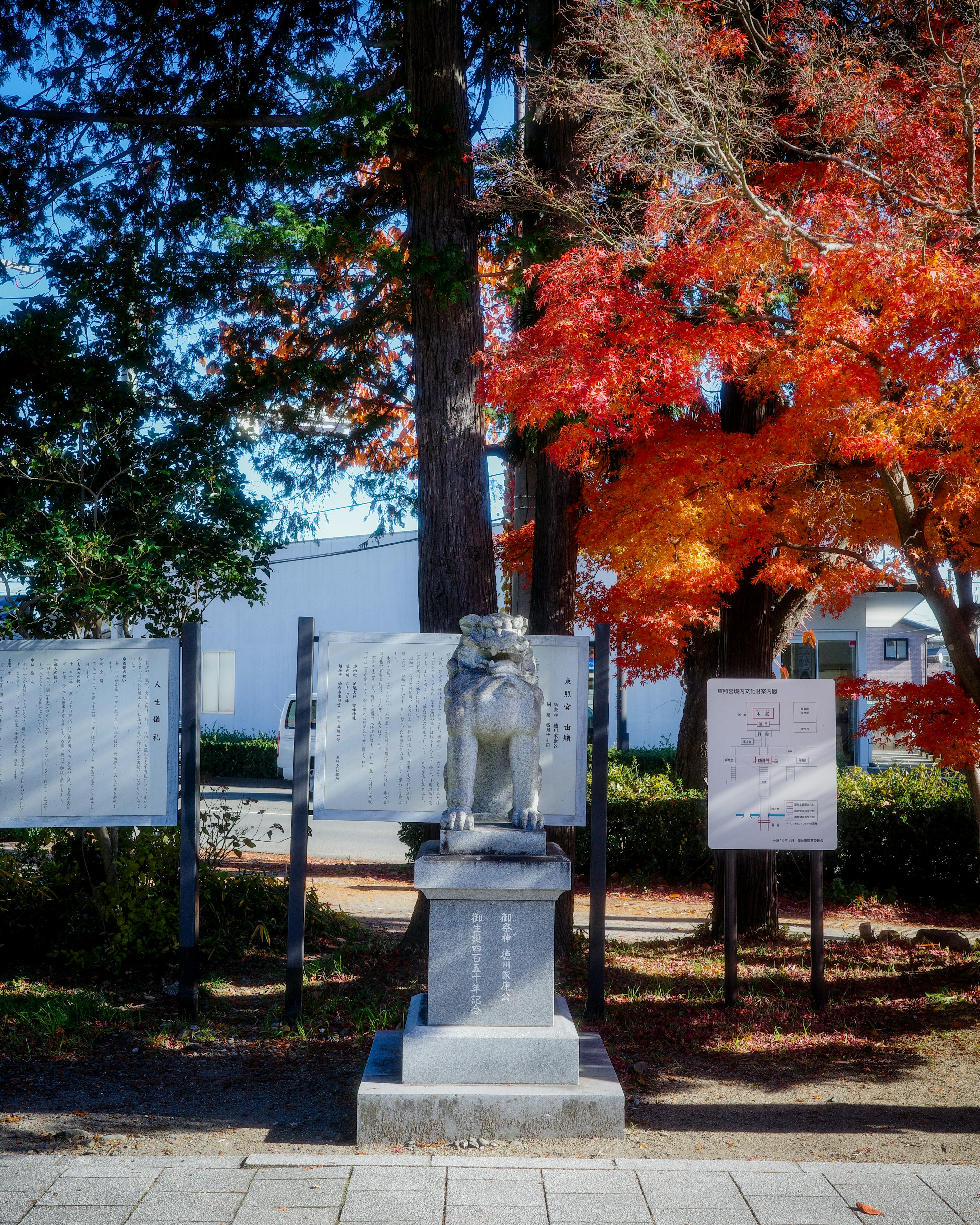 Une statue en pierre d'un lion gardien entourée de feuillage d'automne éclatant