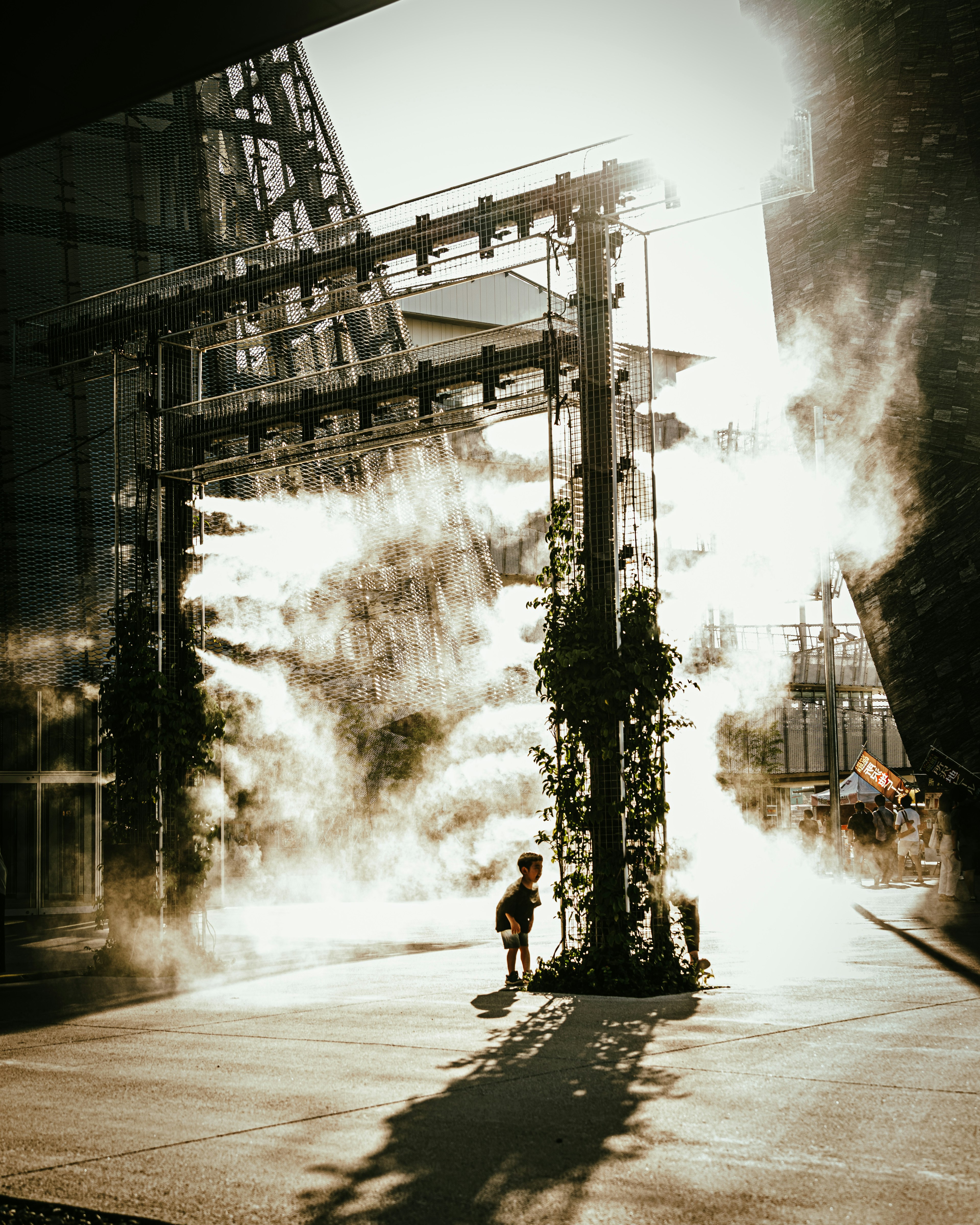 Child standing in mist with silhouetted structures in the background