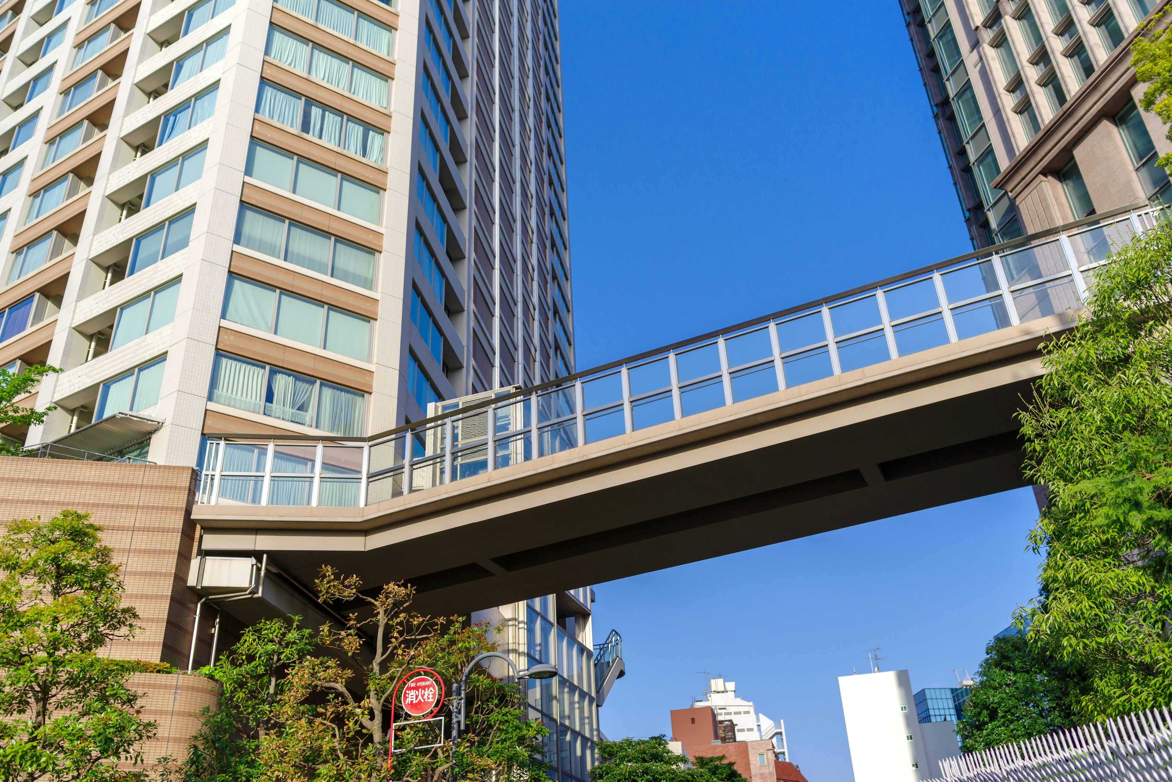 Pedestrian bridge between high-rise buildings under a clear blue sky