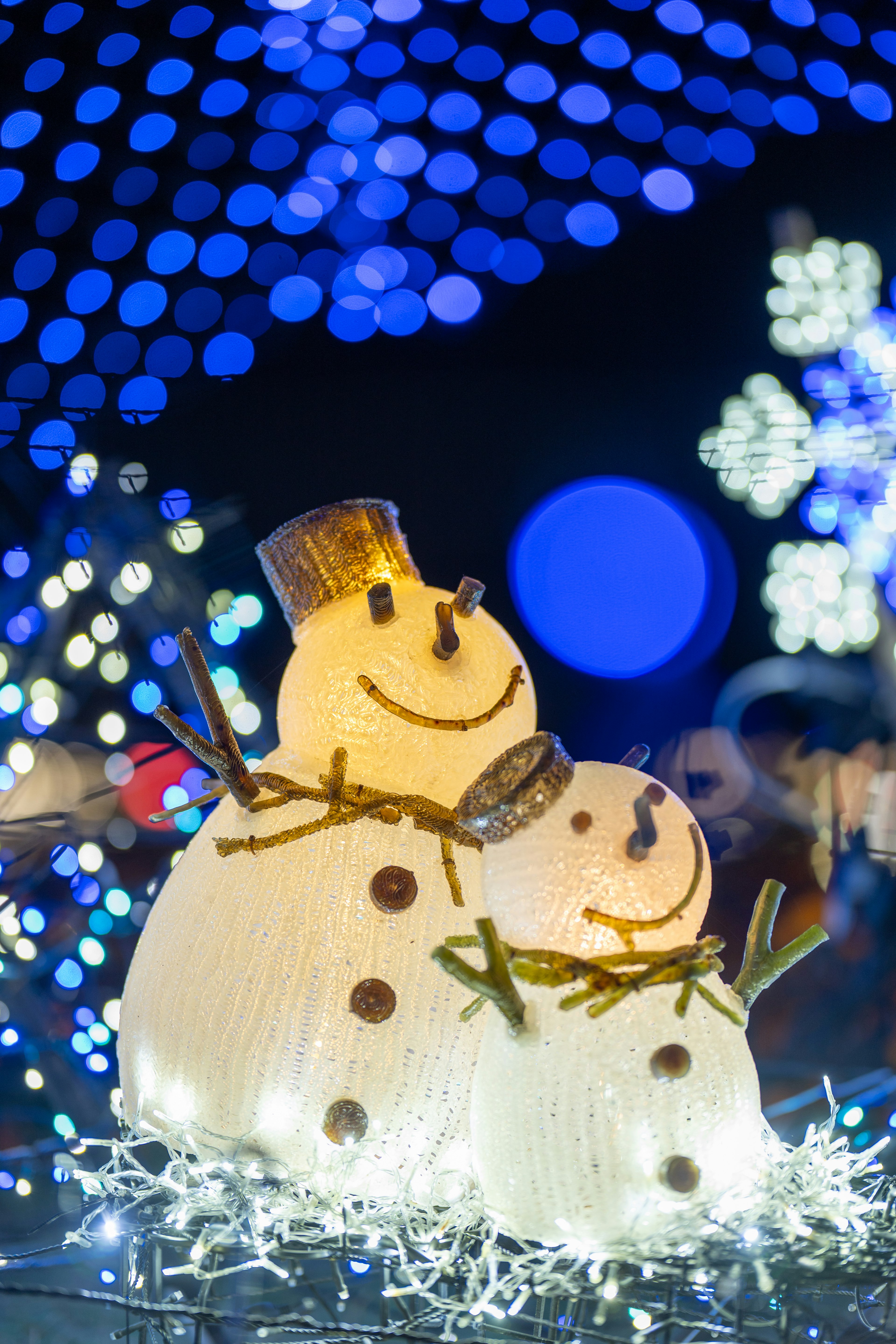 Decorative snowmen with a glowing blue background and festive lights