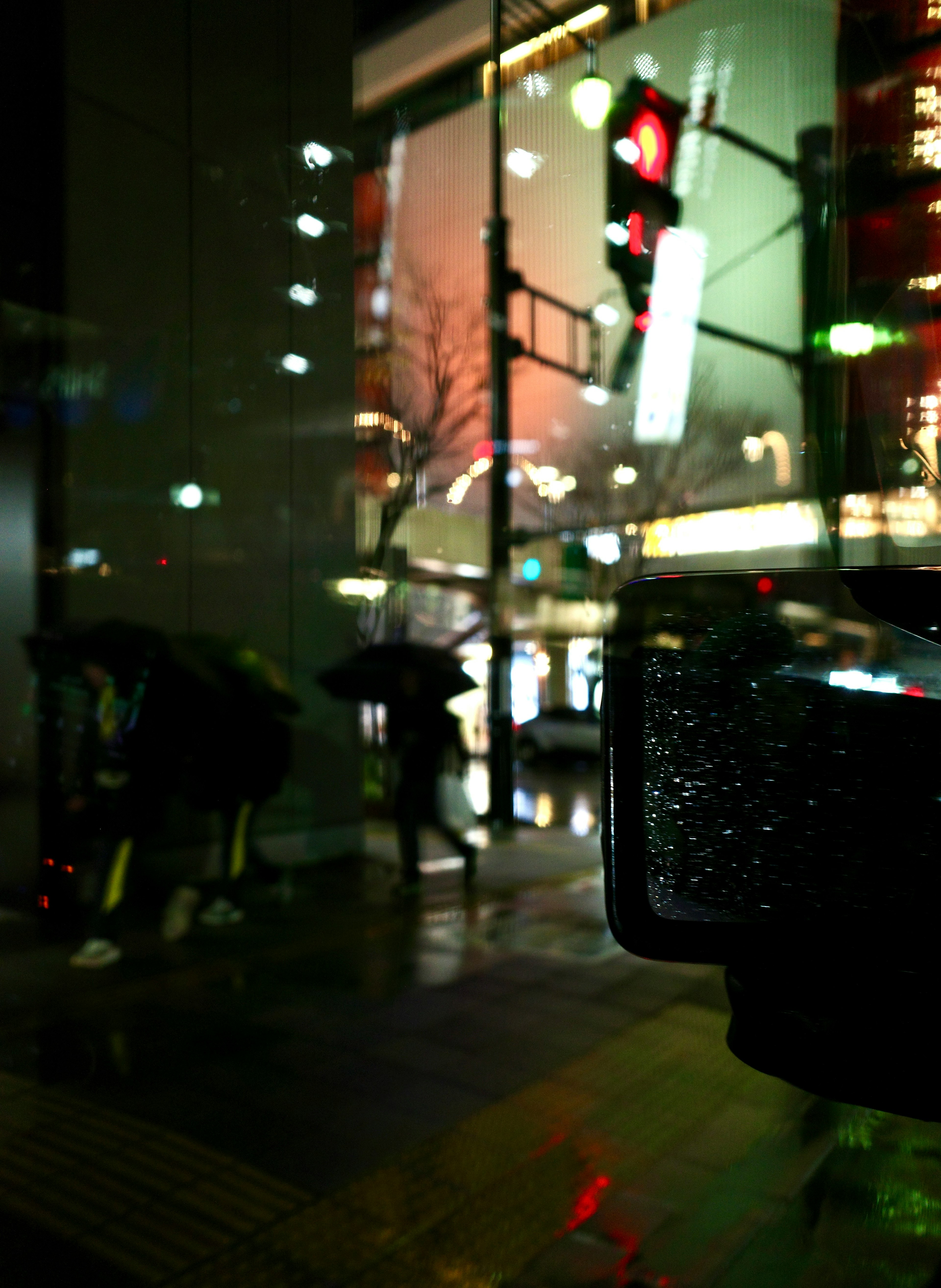 雨の中で傘を差した人々が見える夜の街の風景