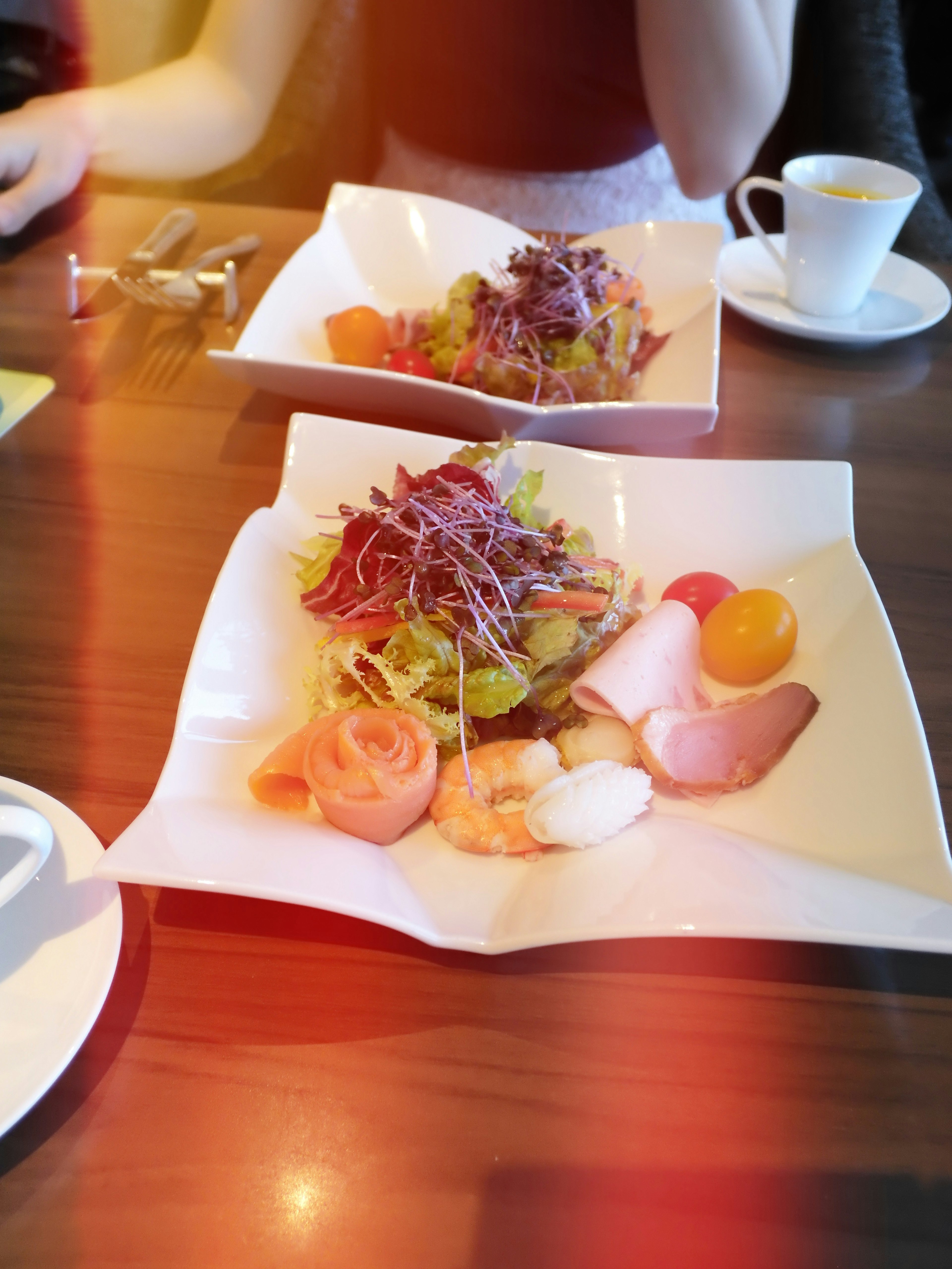 Piatto di insalata colorata e prosciutto disposto su un tavolo di legno