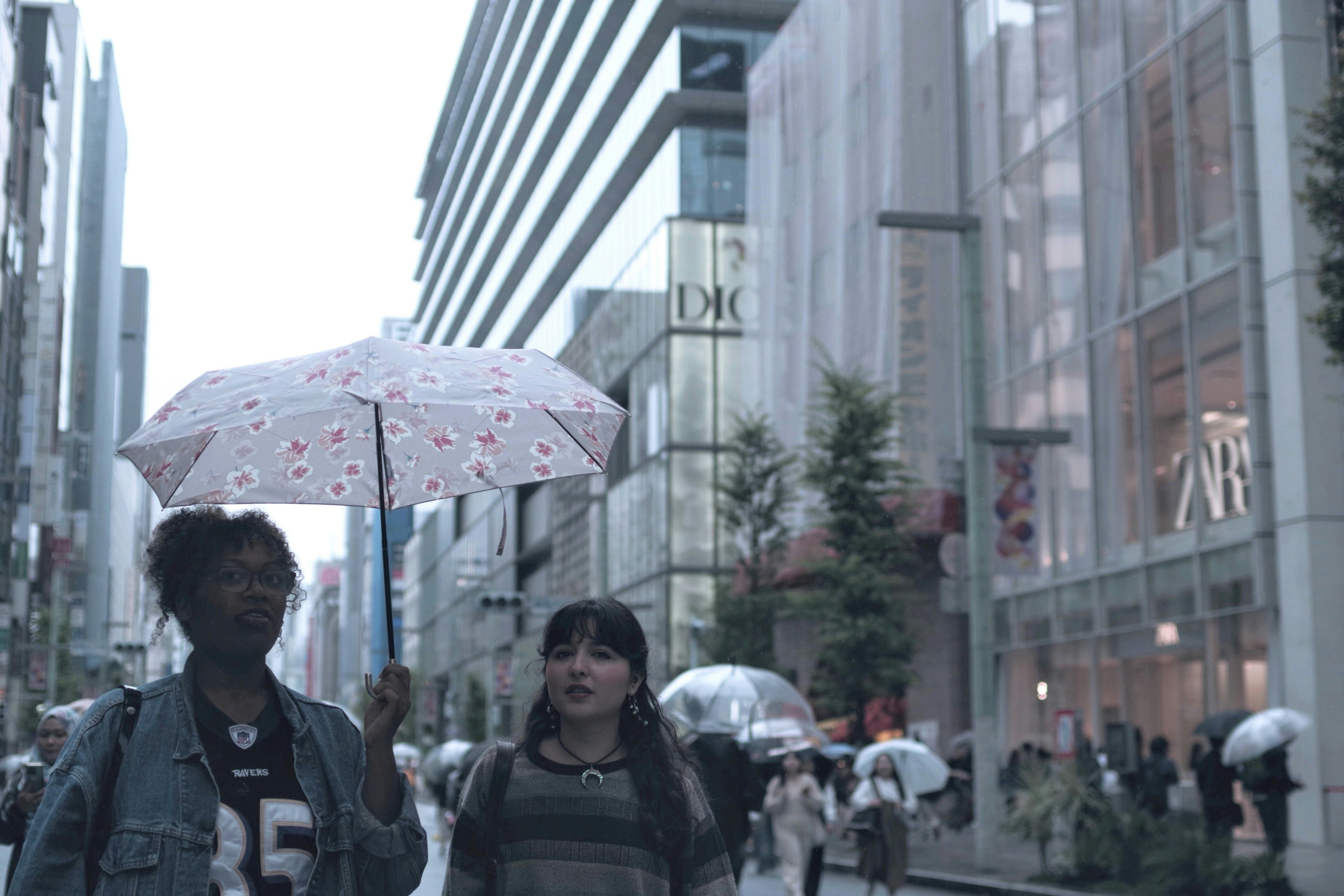 两位女性在雨天撑着伞走在城市中