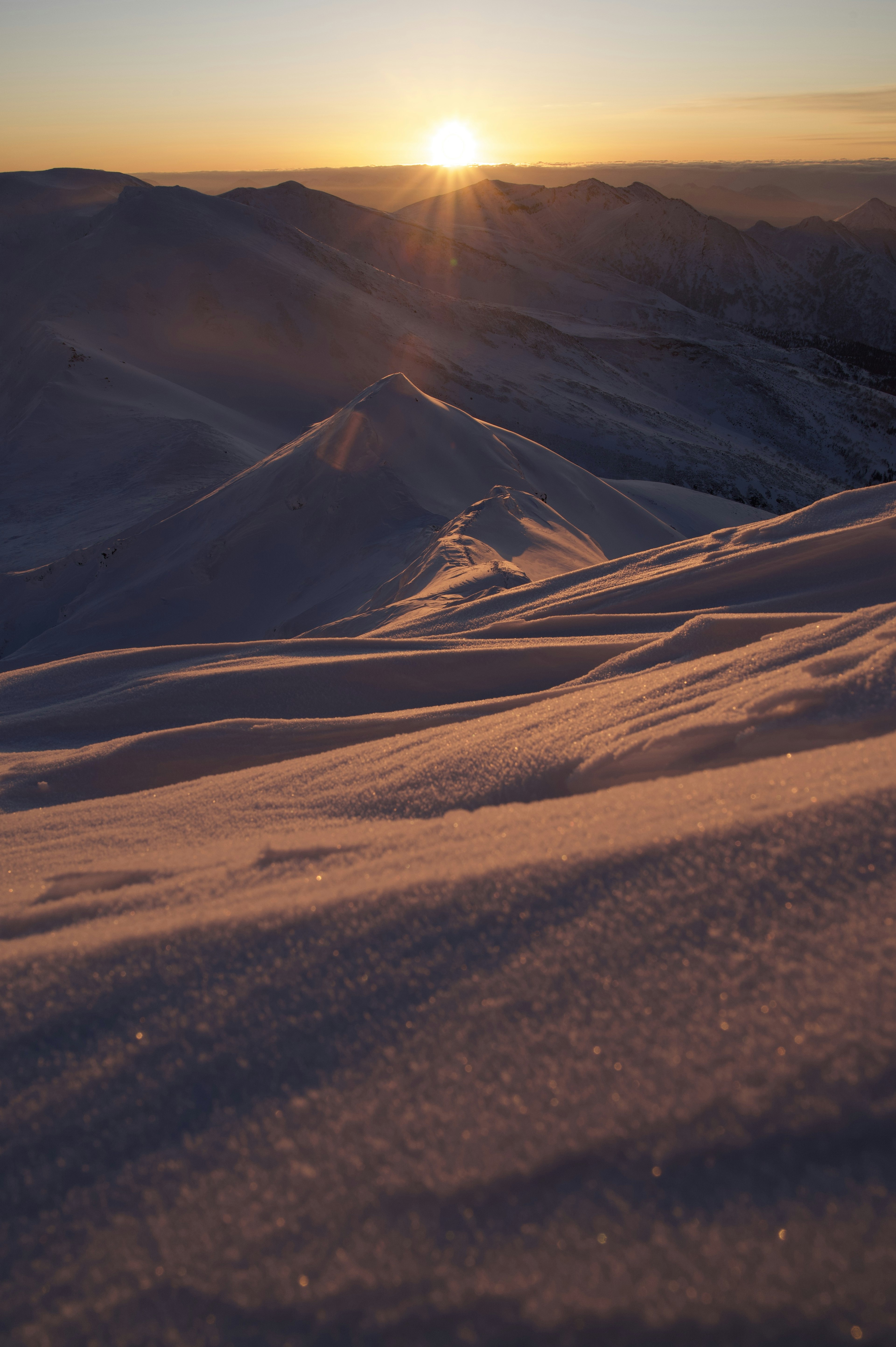 Montañas nevadas con un atardecer de fondo