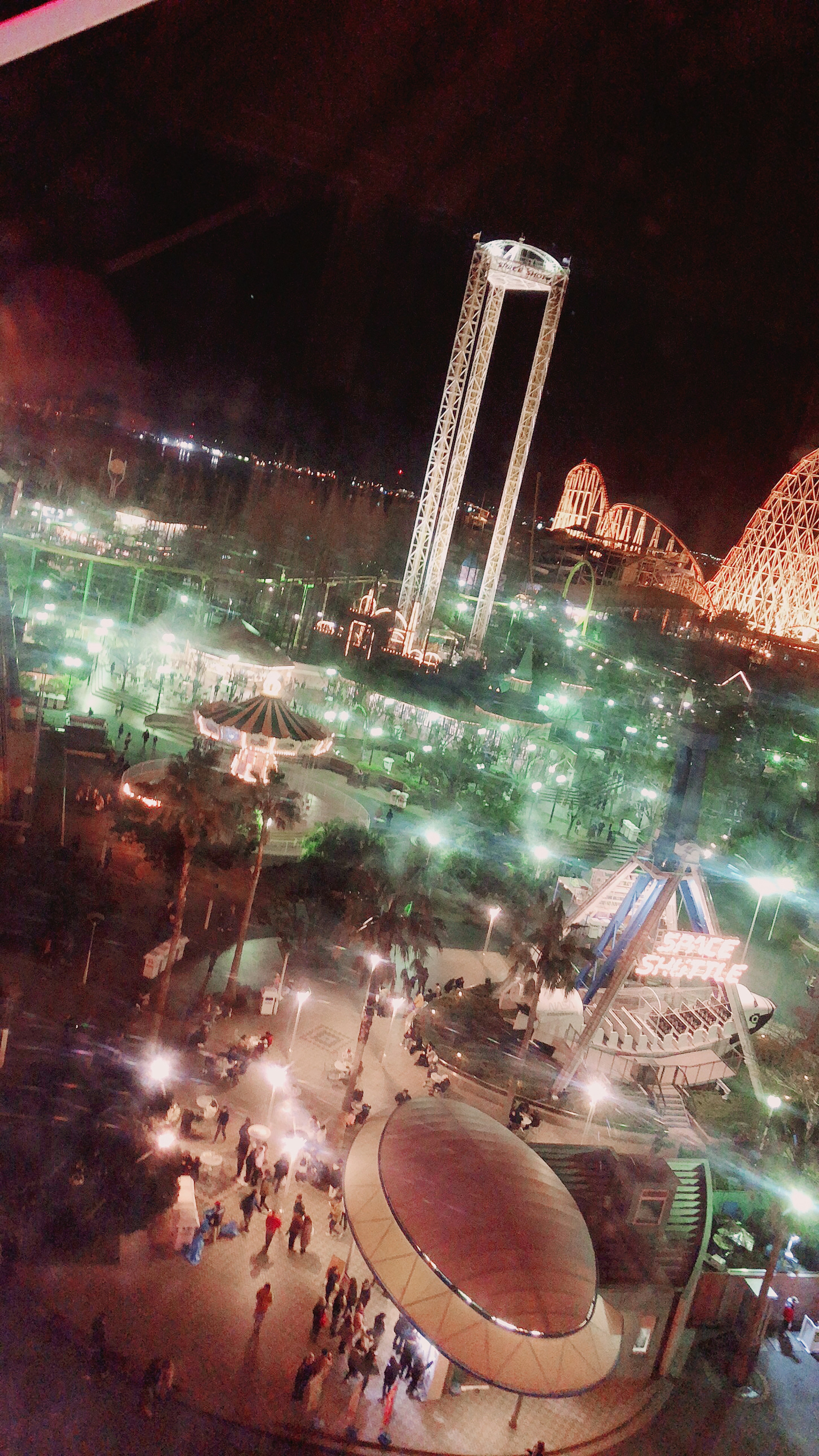 Aerial view of a brightly lit amusement park at night featuring rides and visitors