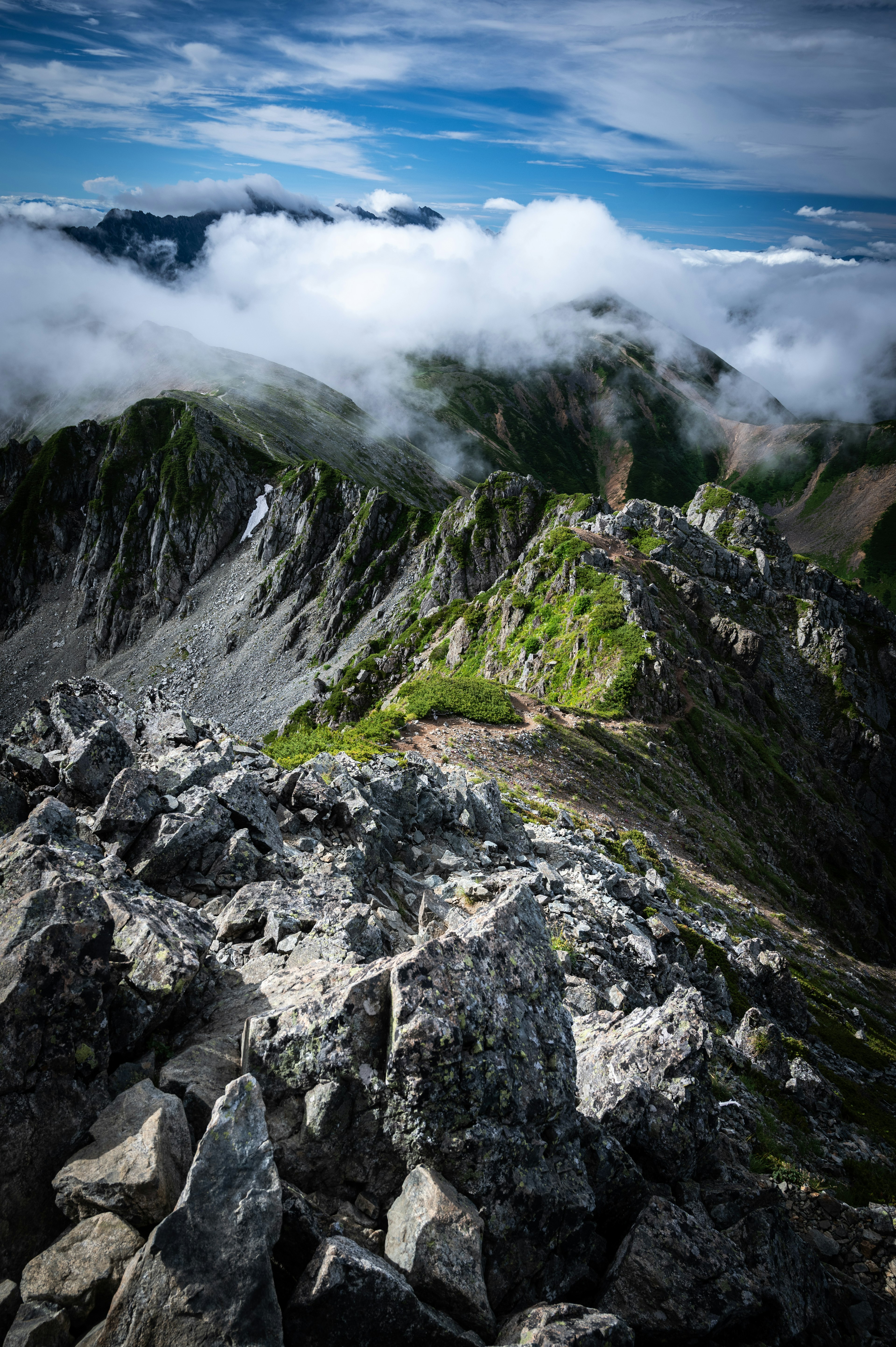 Vista dalla cima della montagna con rocce appuntite e erba verde