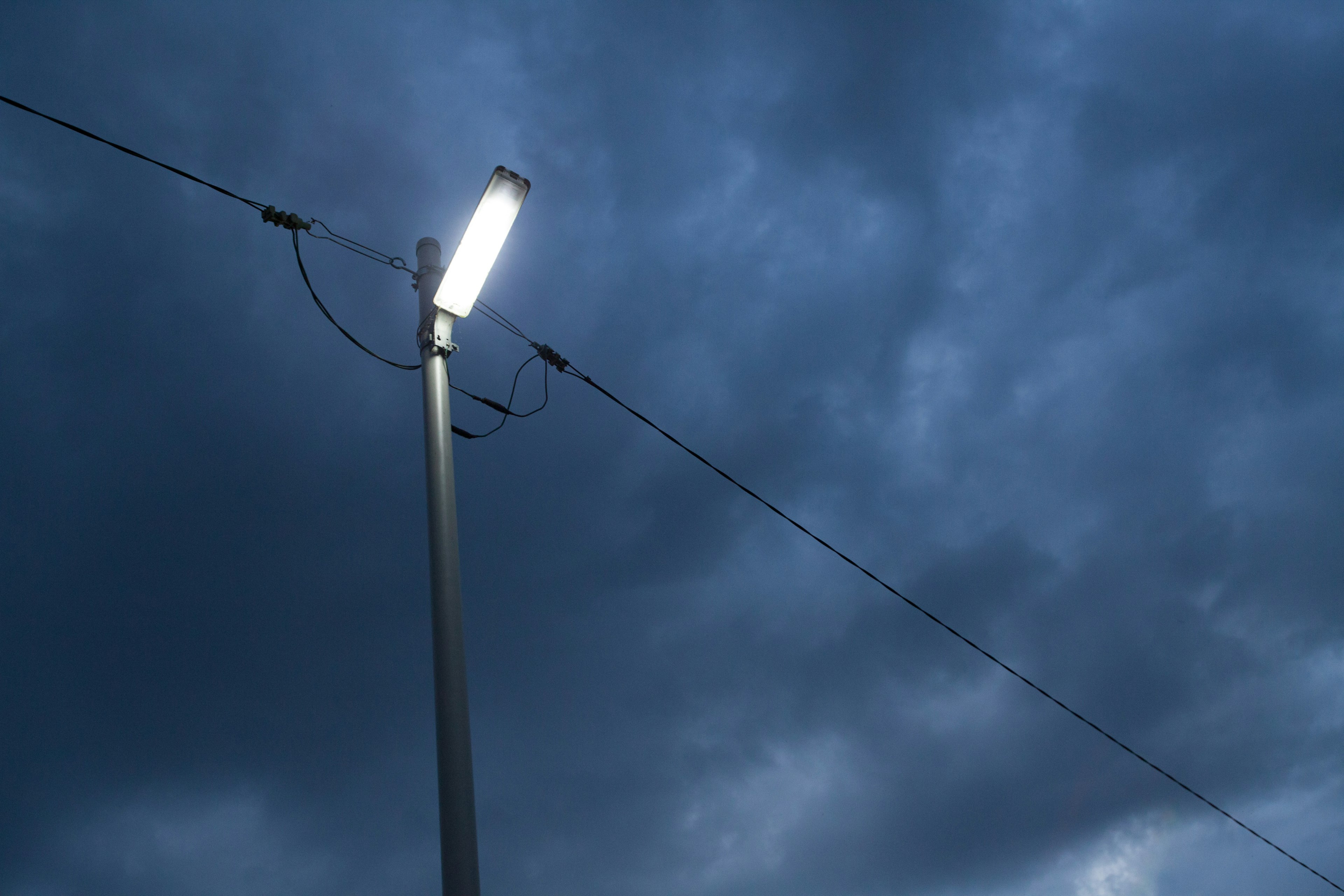 暗い空の下に立つ街灯と電線の写真