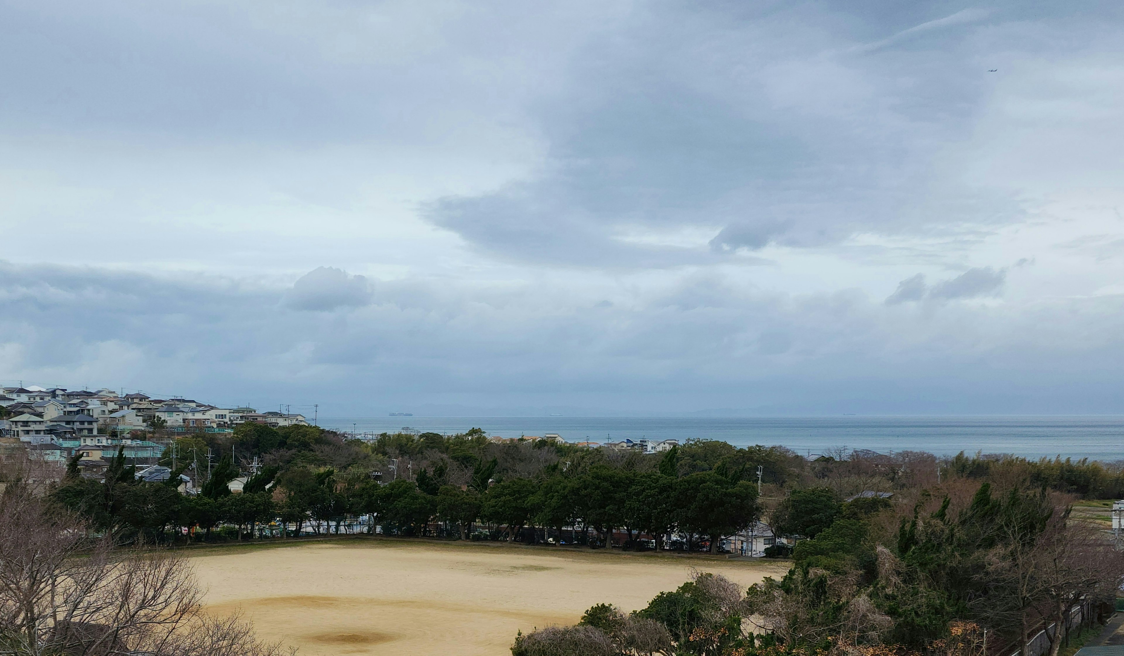 Bewölkter Himmel über einer Küstenlandschaft mit Bäumen und Strand