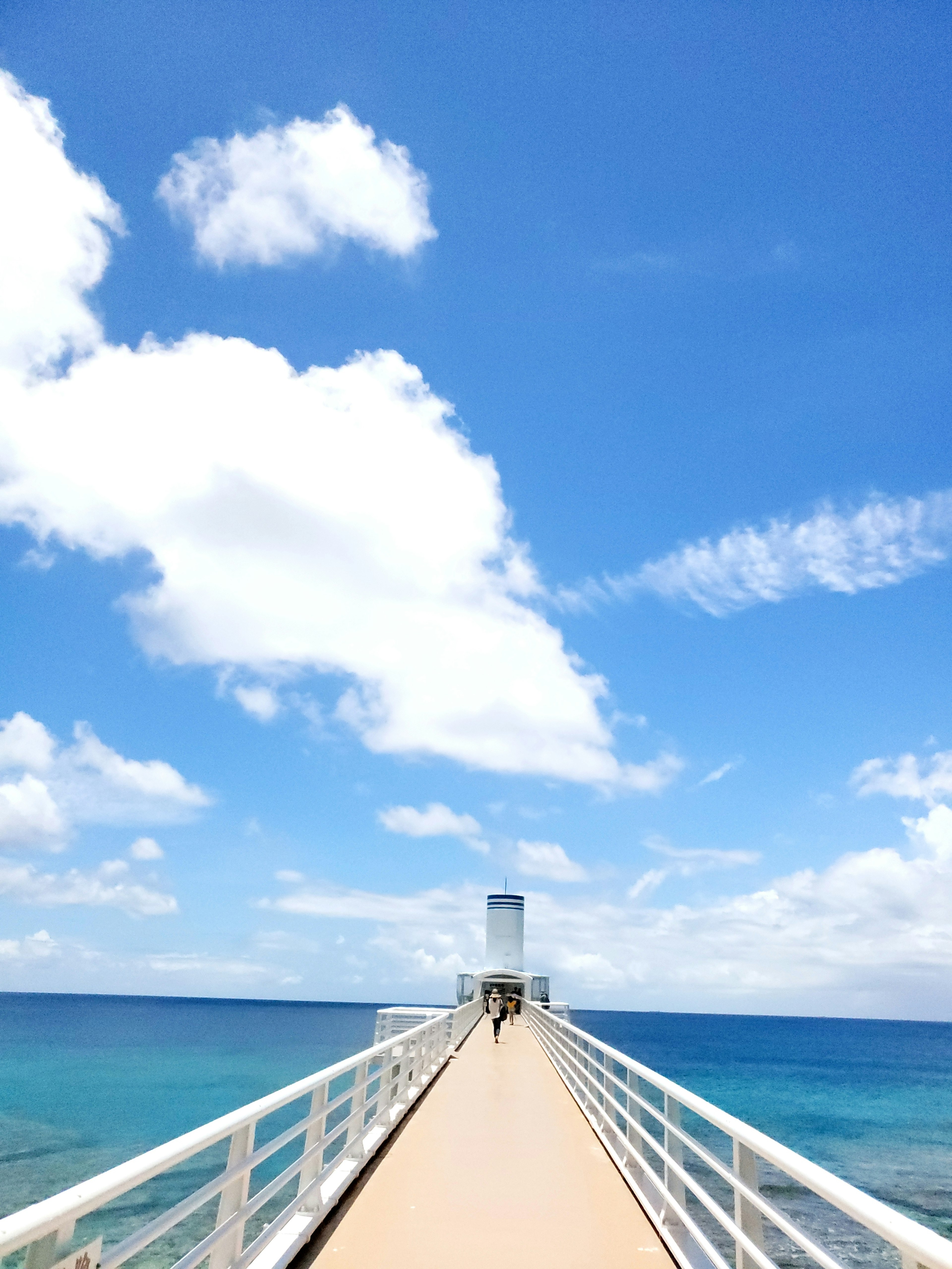 Long pier extending into the blue sea under a bright sky