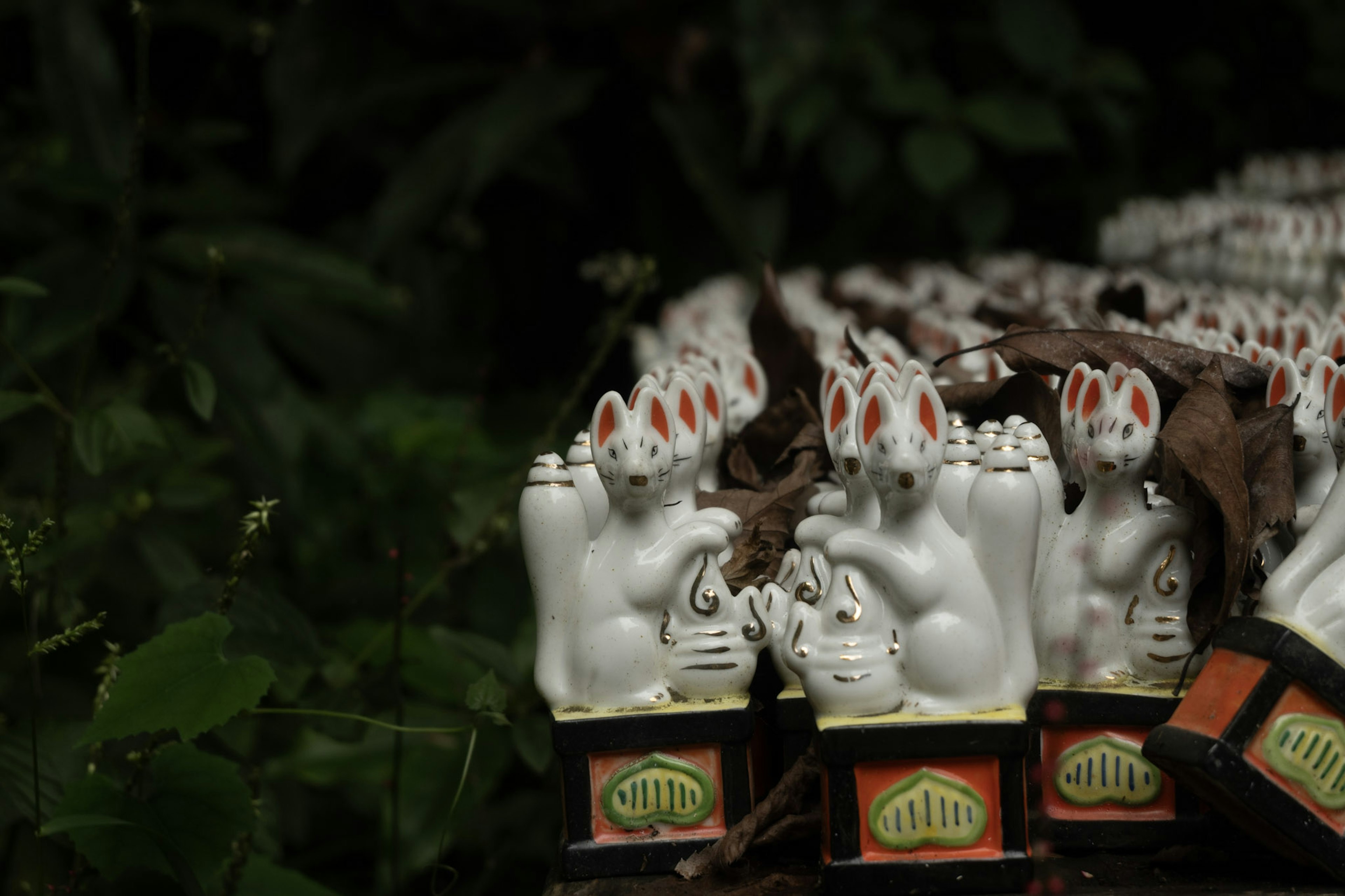 Rangée de figurines de lapins en céramique blanche avec des accents rouges sur un fond vert