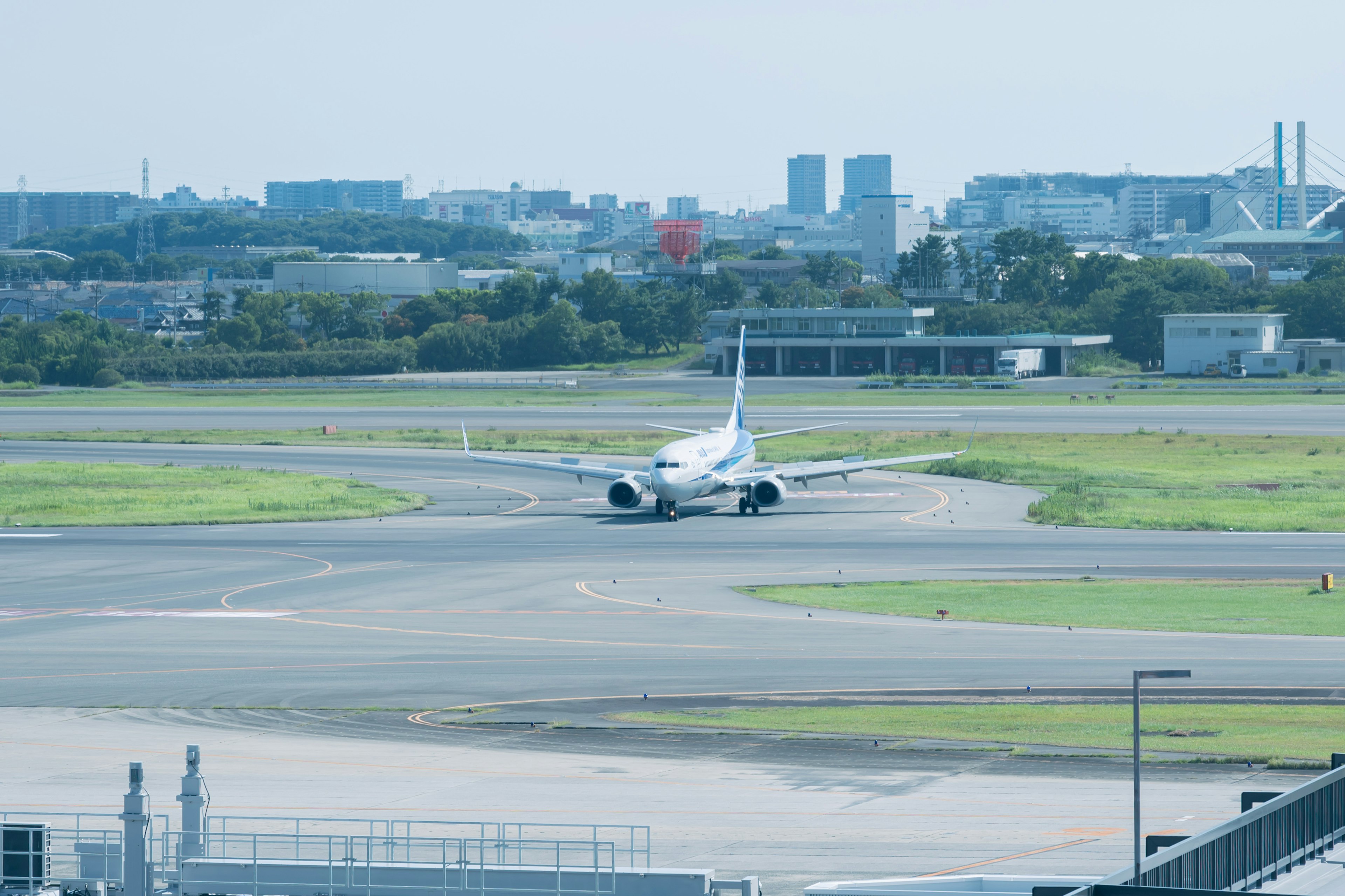 Airplane taxiing on runway with cityscape in the background